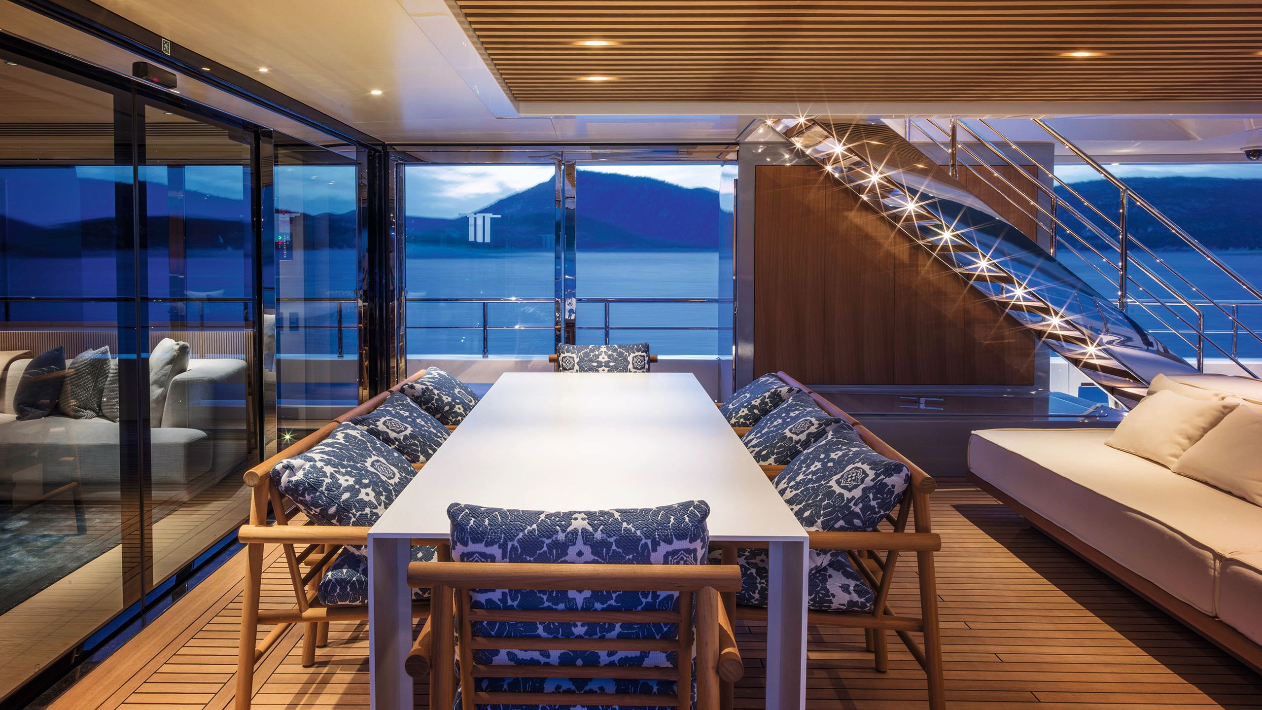 Indoor dining table with chairs surrounding. The top of the table is white and the chair cushions are white with a blue floral pattern