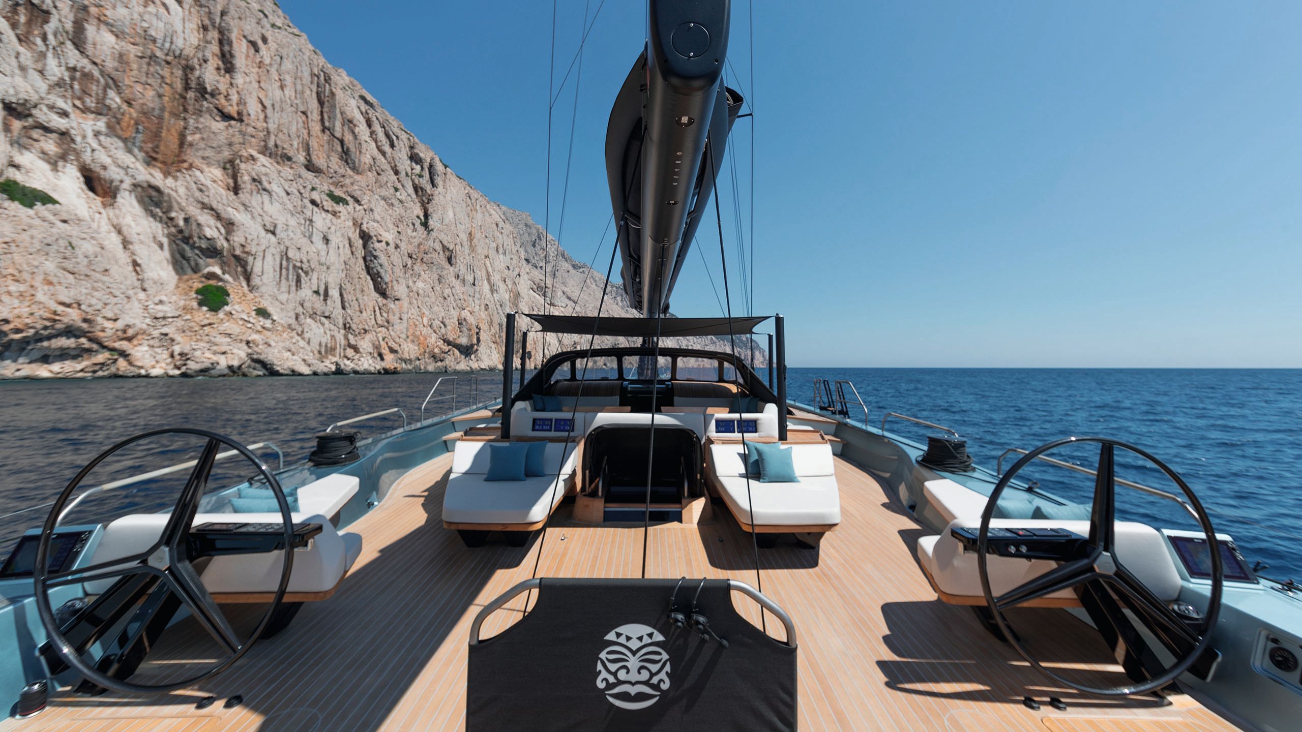 Two black steering wheels either side of the deck and sun loungers in the background