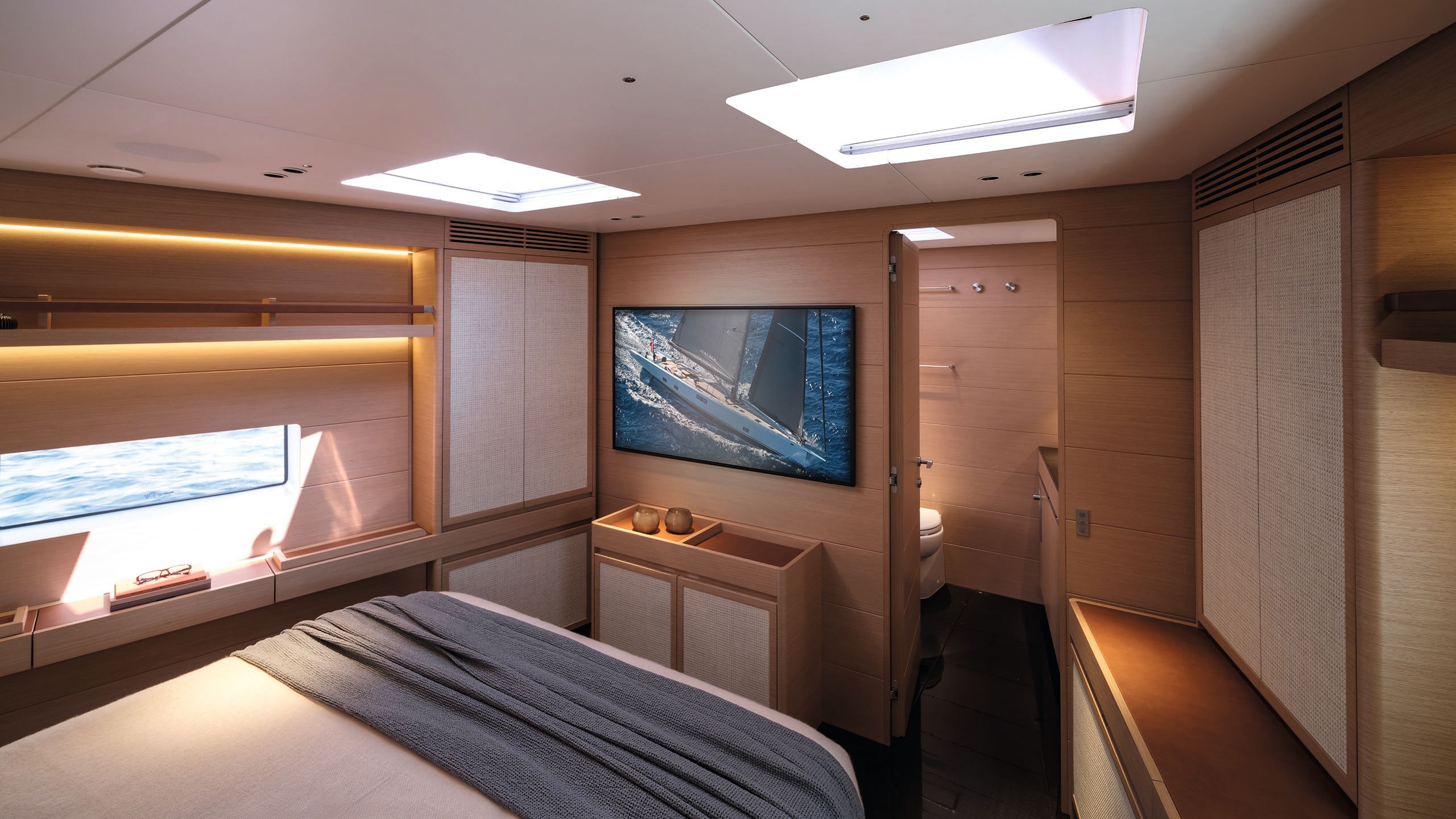Inside the owner's suite, looking towards the en suite door. There's a TV on the wall and a blue throw on the bed