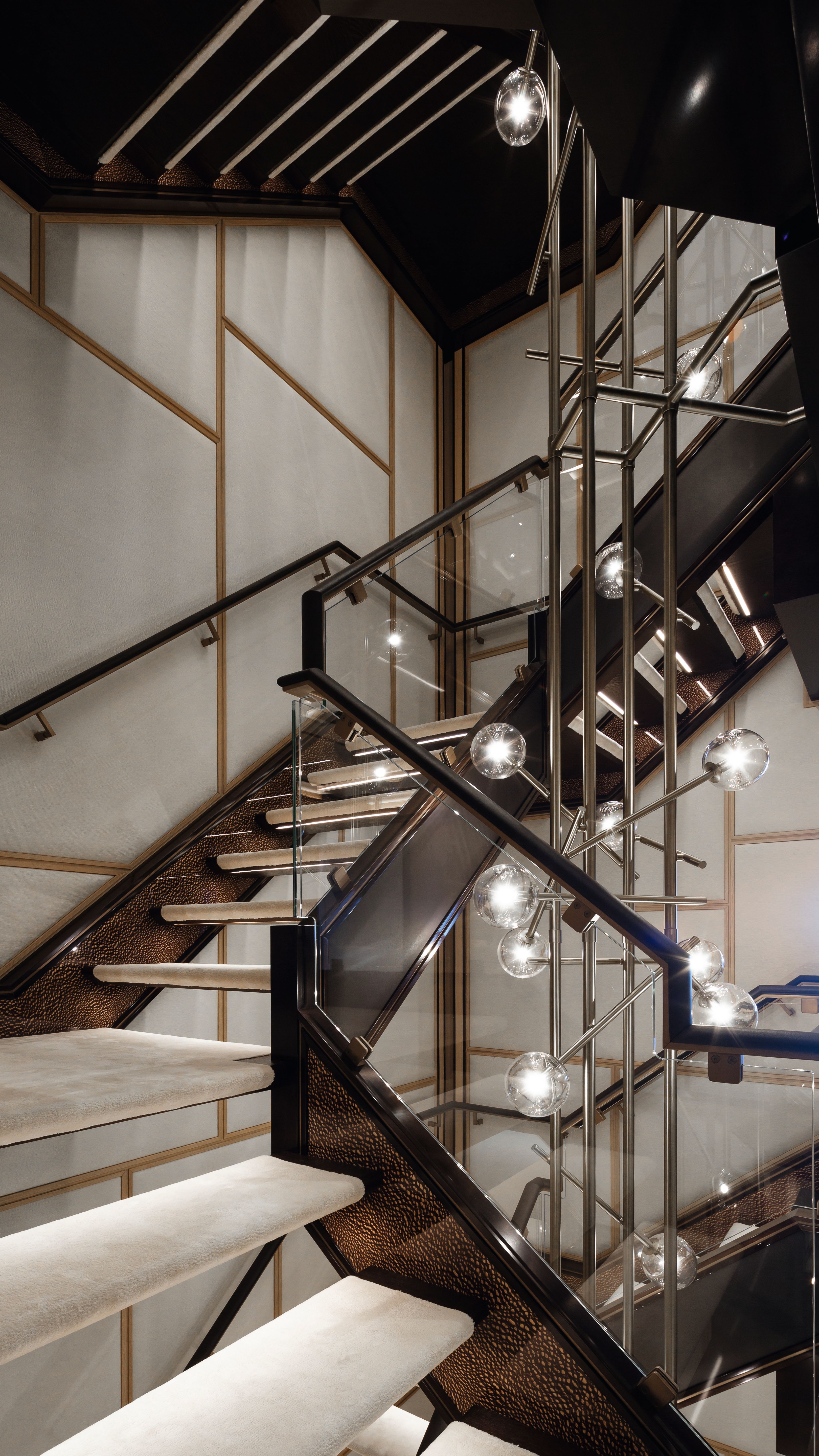 Staircase with dark wood/black bannisters and lighter treads with modern globe light fittings