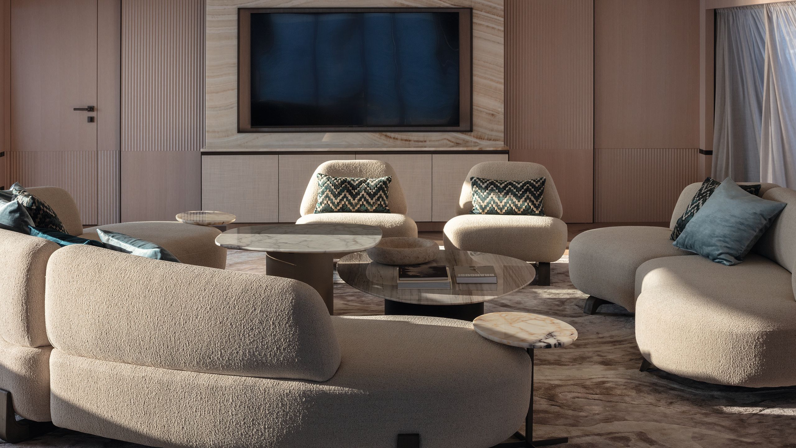 Lounge area on Frette with curved seating in muted neutral colours and blue and white chevron cushions