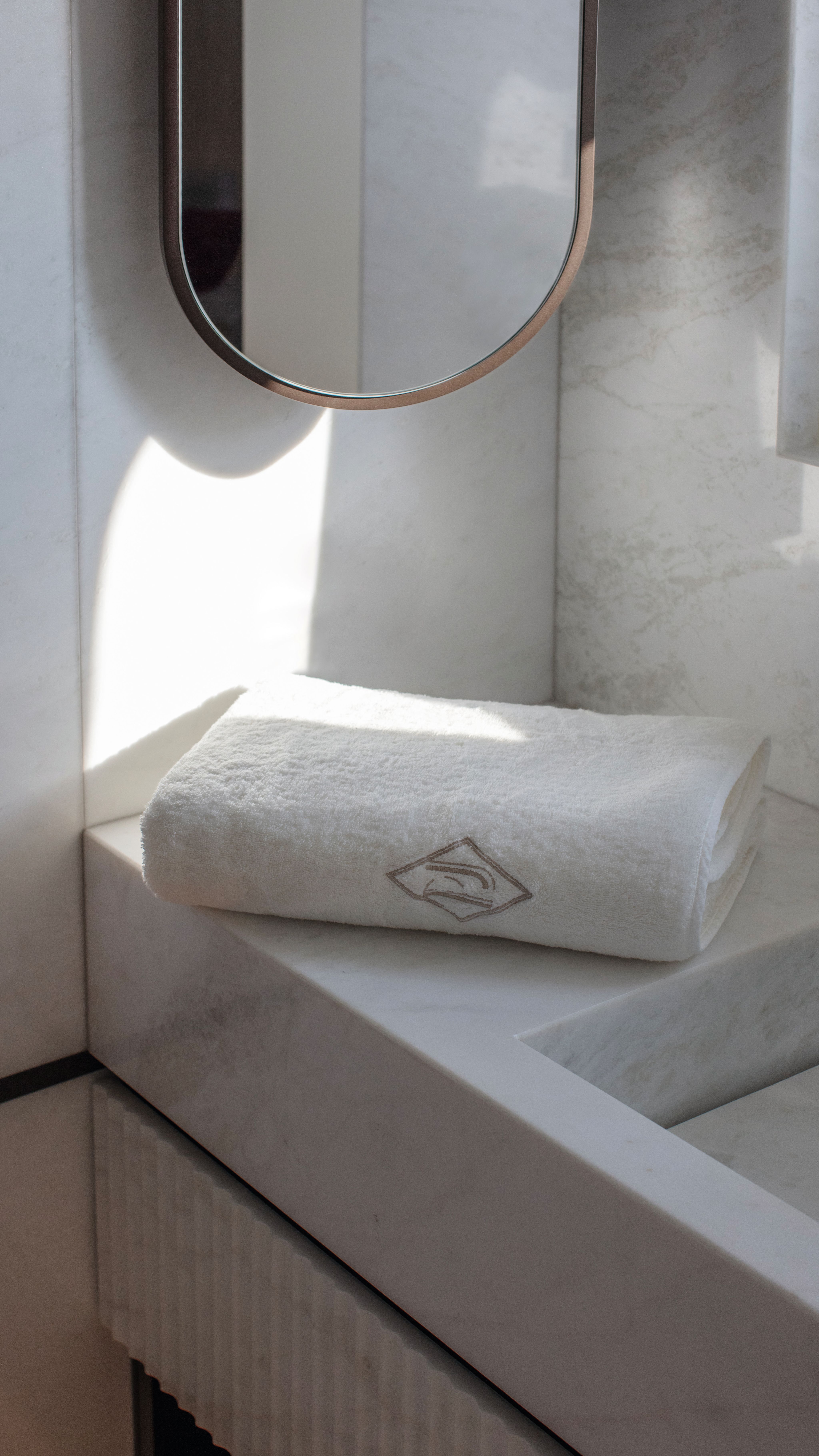 Folded white towel on the side of a sink