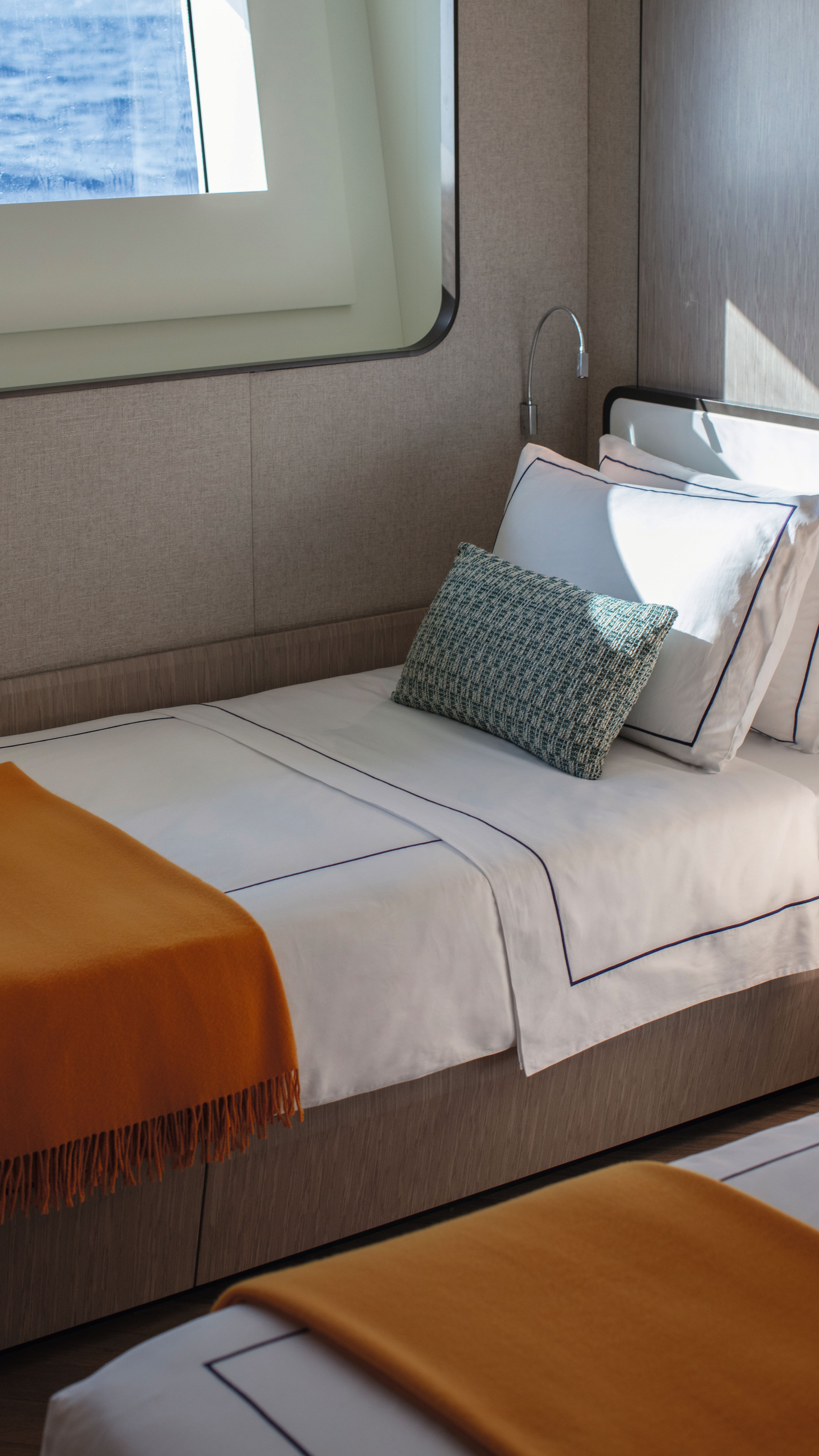 A twin-bed guest suite with the same white linens as the main bedroom and an orange throw