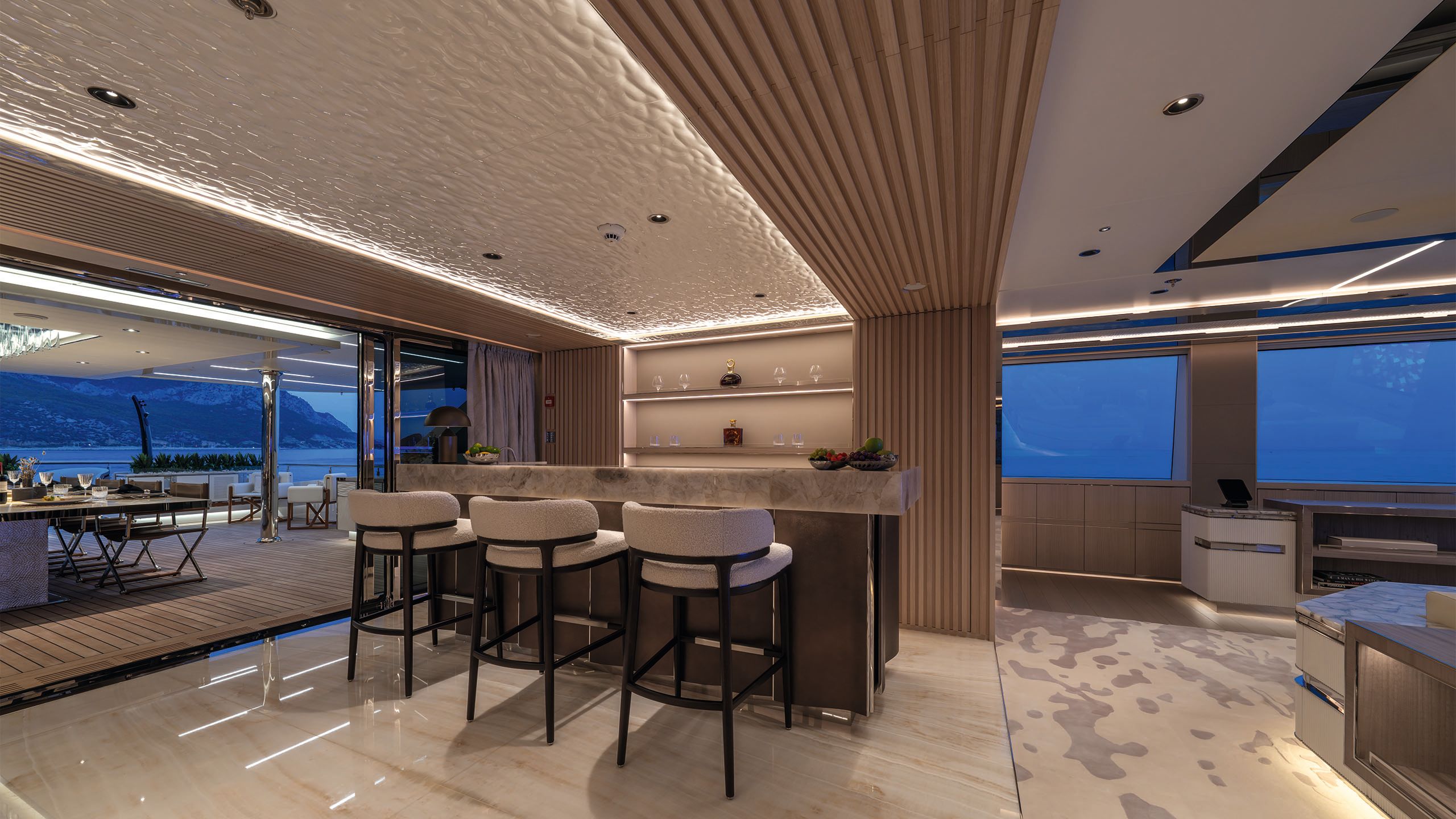 A grey, marble-topped bar with three tall stools