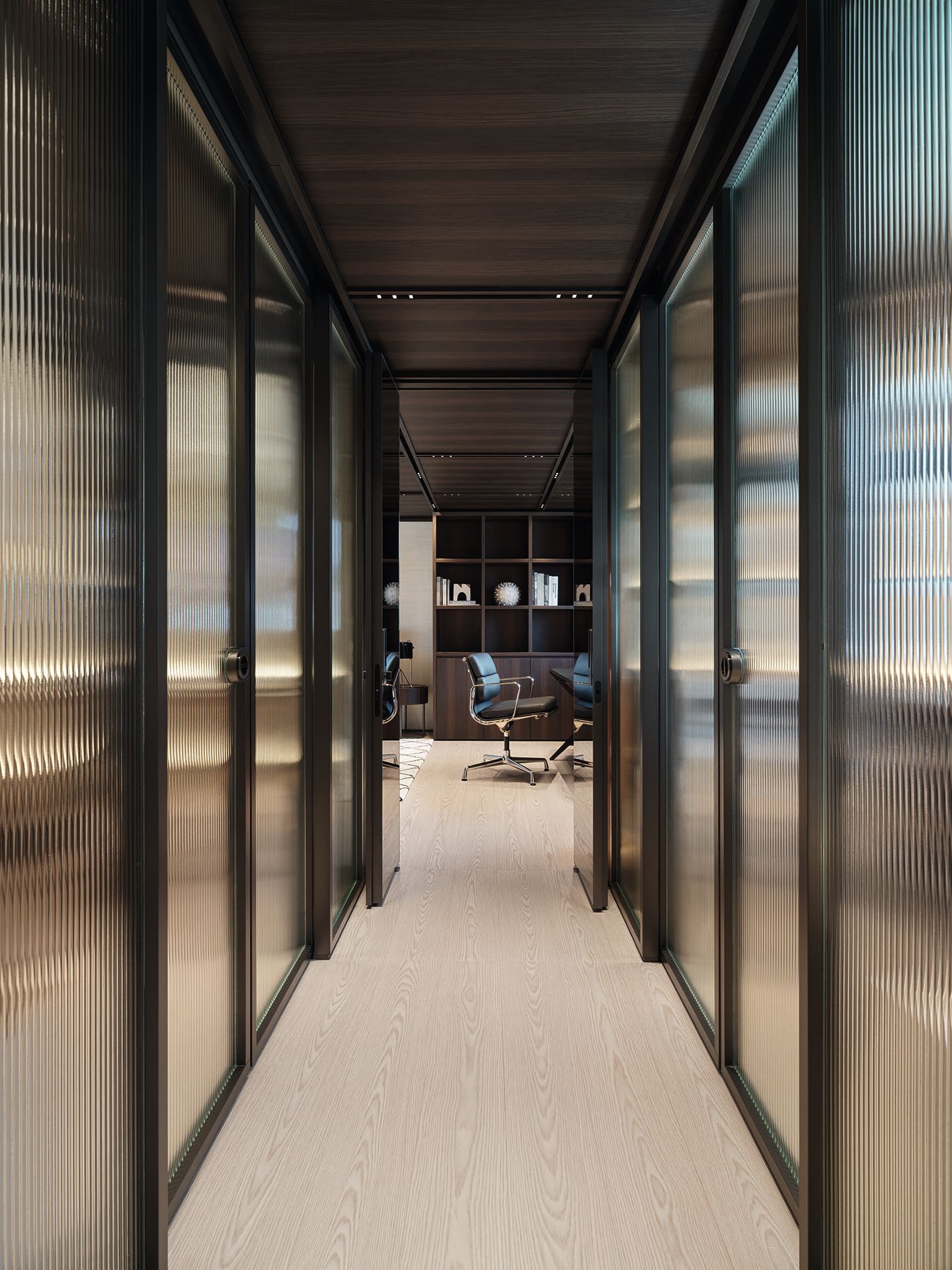 Reeded glass doors either side of a corridor, looking towards a black and chrome chair