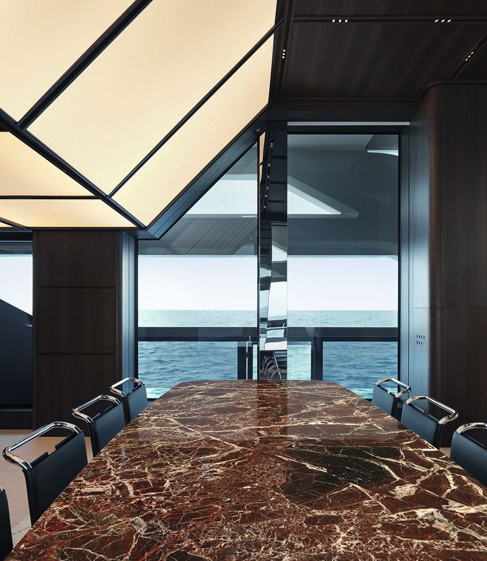 Long view of the dining table which has a brown marbled effect and black and chrome seats