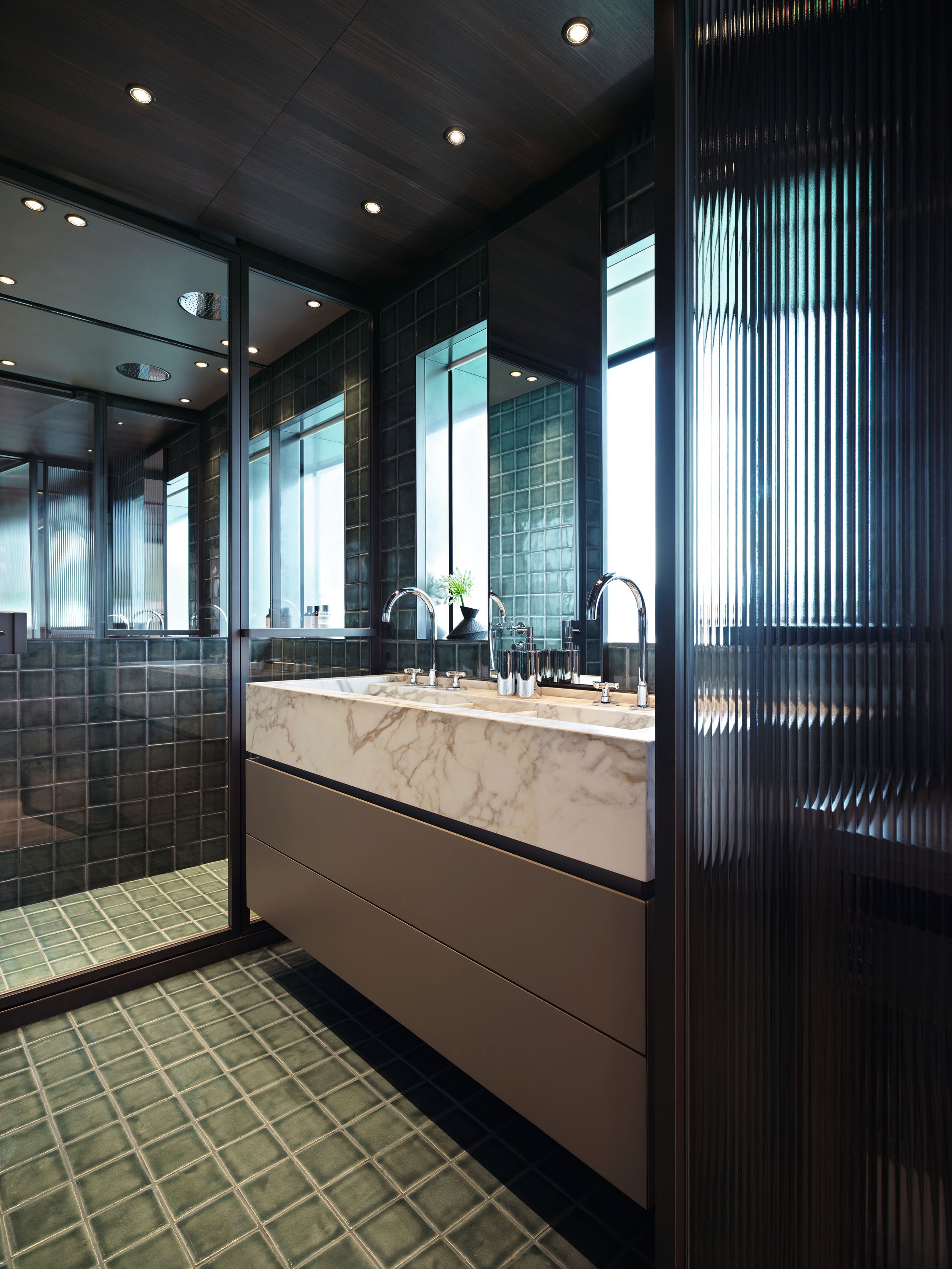 Close-up of double vanity sink in cream marbled effect with chrome taps, black fluted glass and green wall tiles
