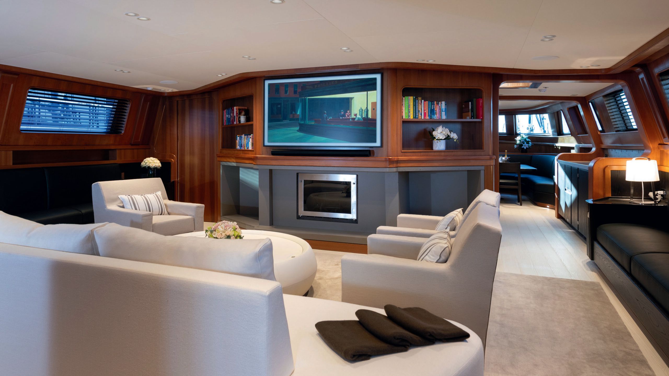 Interior of the lounge area, which has a white sofa and three white armchairs. There's a TV on the wall.