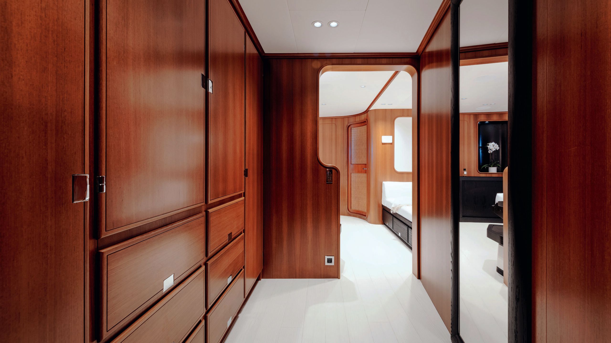 Looking down a hallway which has teak cupboards and storage along it