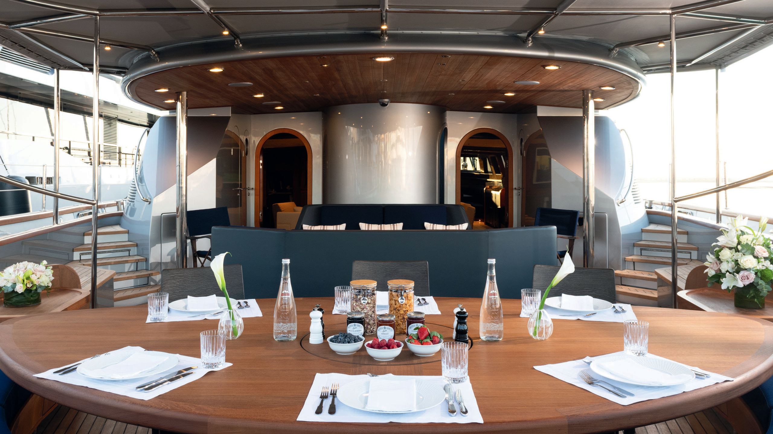 Large dark wood table with place settings, bottled water, fruit and cereal