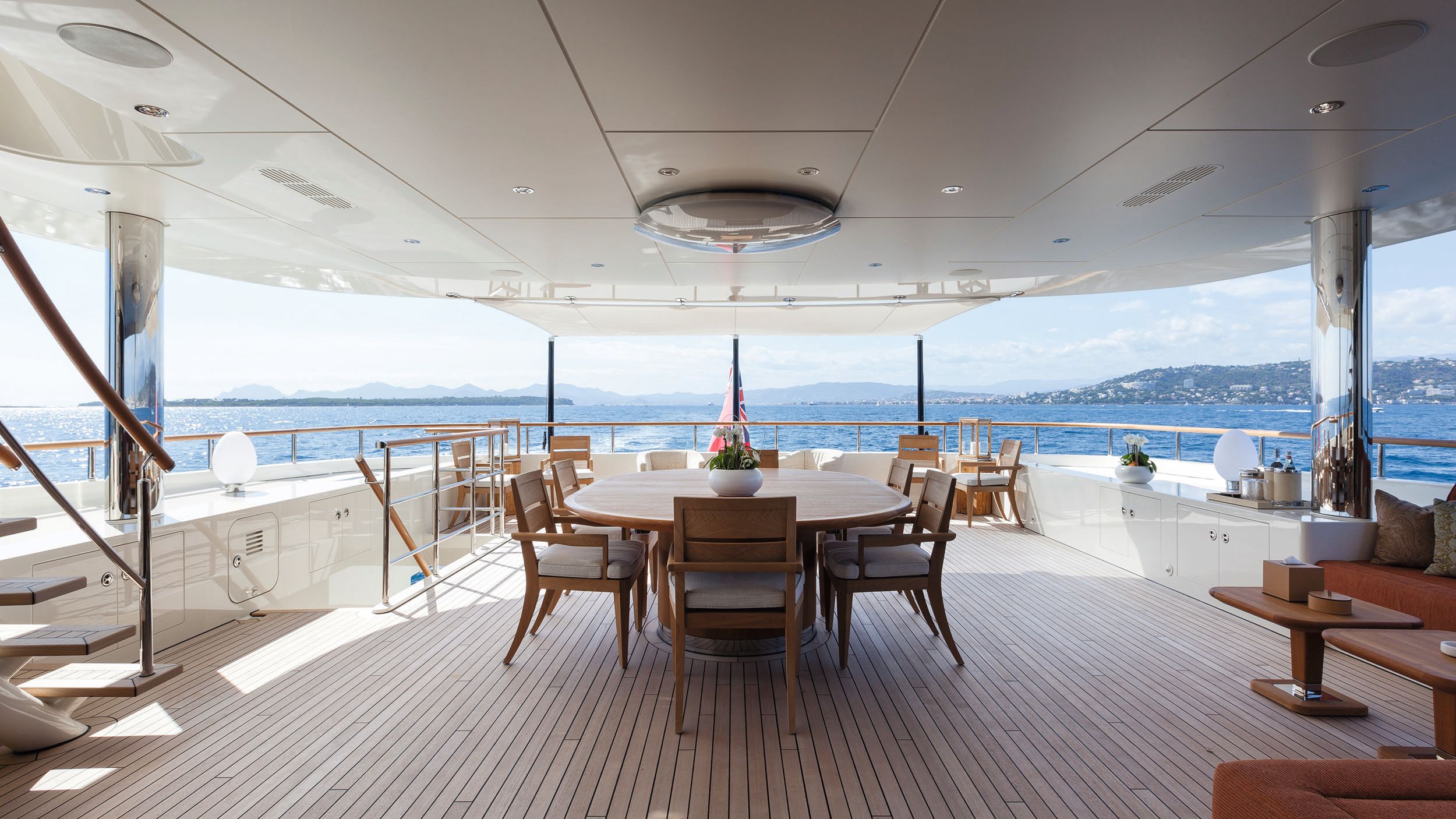 Pre-refit bridge aft deck had a light wood dining table set and white storage all around the deck