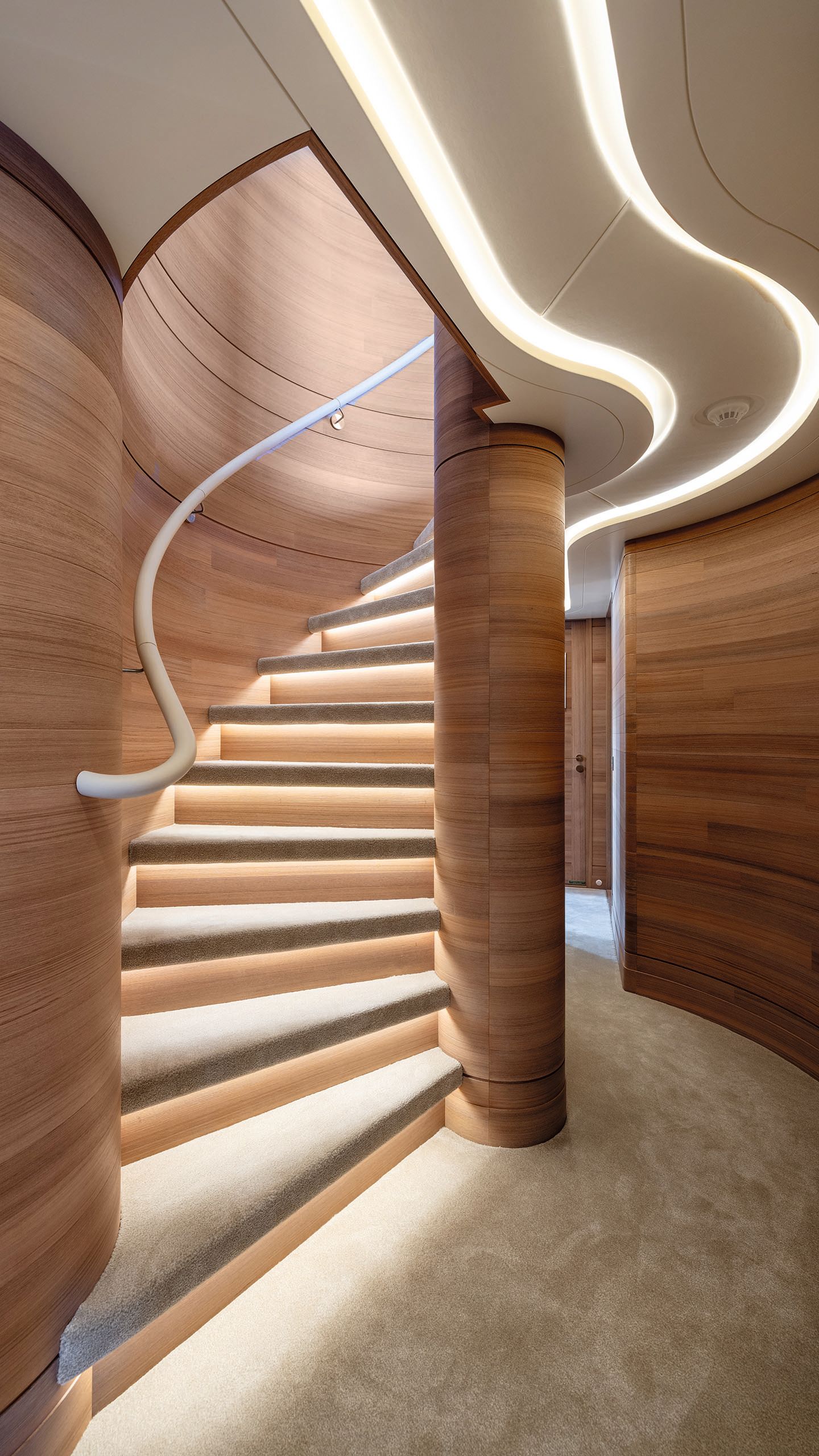 Looking up a staircase from the bottom - the treads are lit from underneath and it has a curved cream bannister