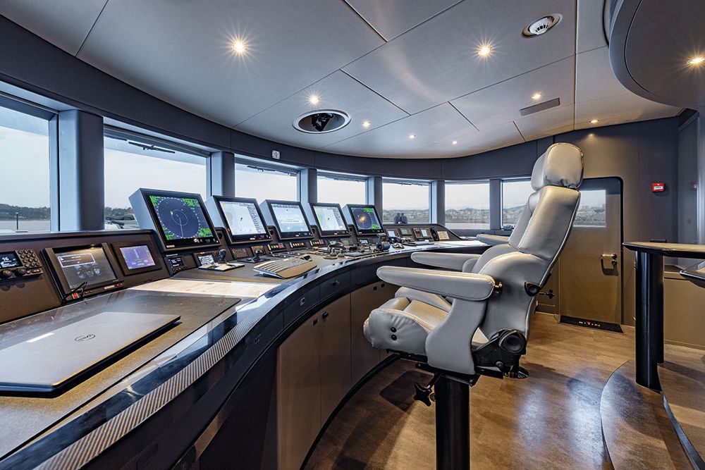 Inside the wheelhouse - there are two chairs in grey leather facing a desk of controls and screens