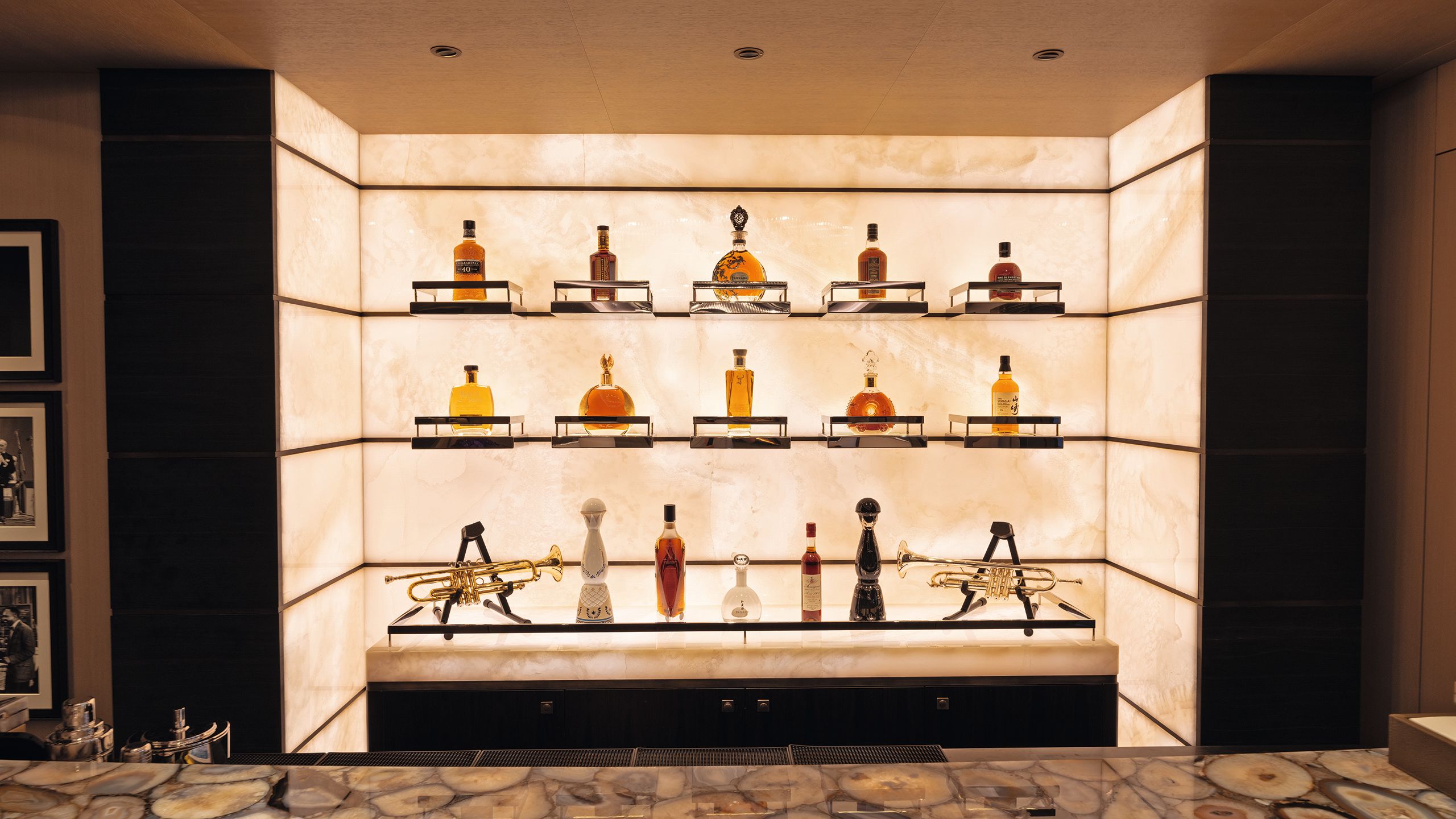 10 bottles on single plinths on backlit walls and five on shelf below