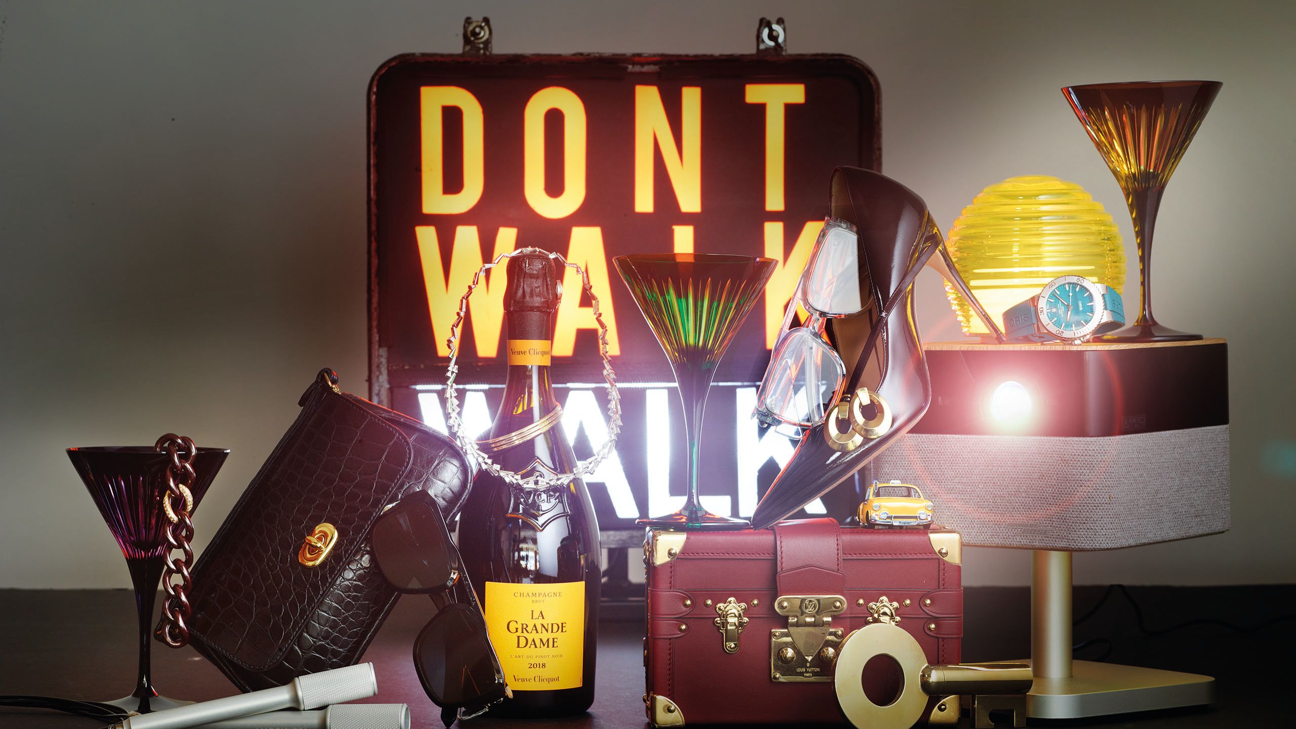 Gift guide in a plum and yellow colour palatte including a "don't walk" street sign, handbag, sunglasses and a pinot noir