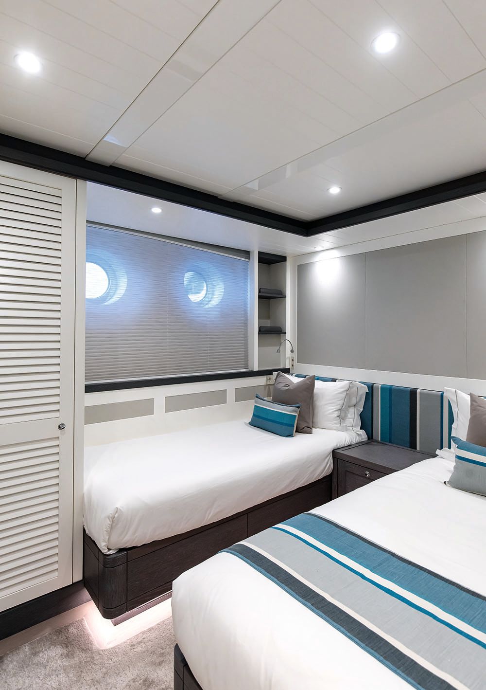 Twin bedroom with white linens and striped headboard and throw