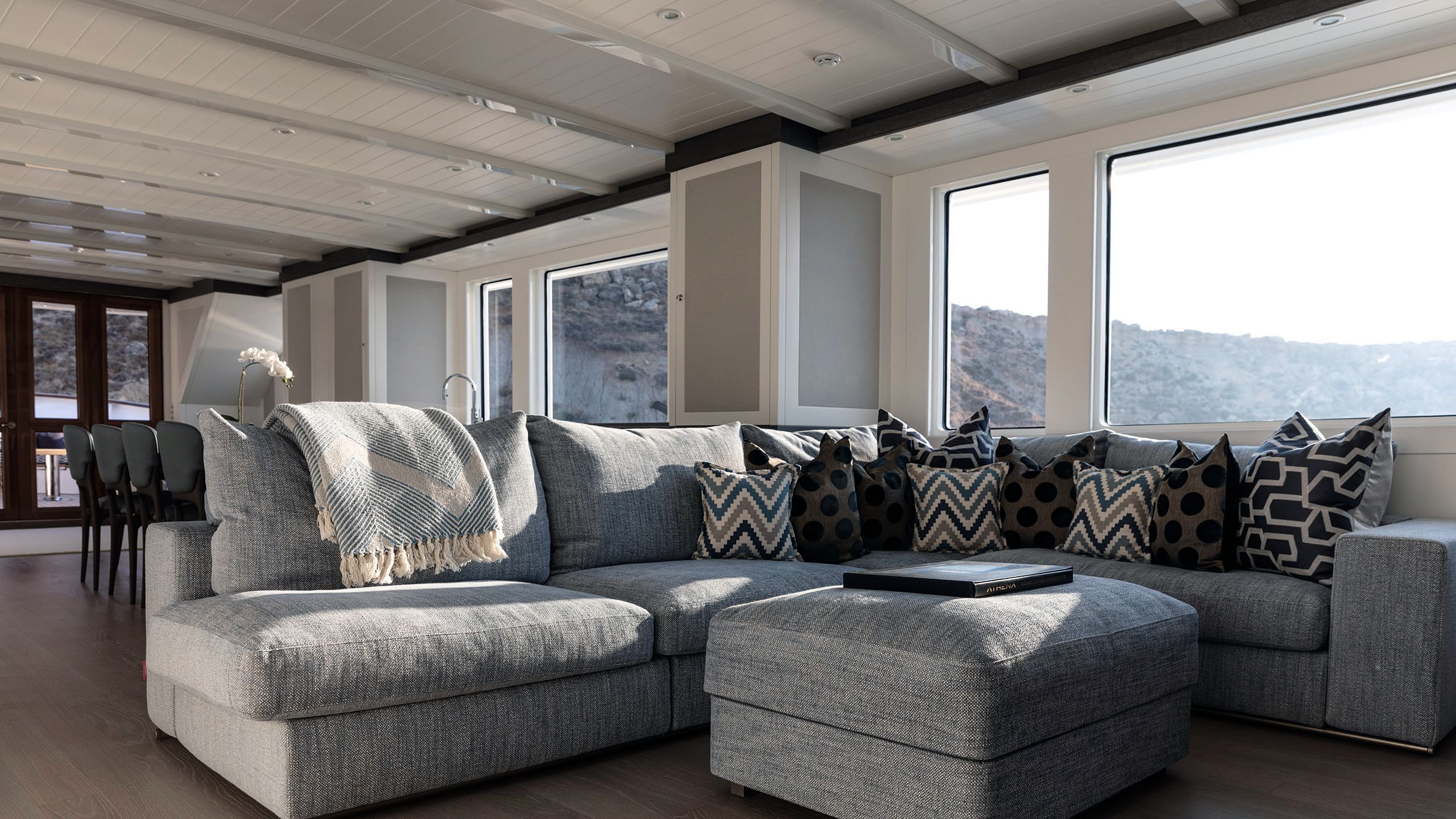 Lounge area inside one of the decks. It has a small curved grey sofa with cushions and blankets