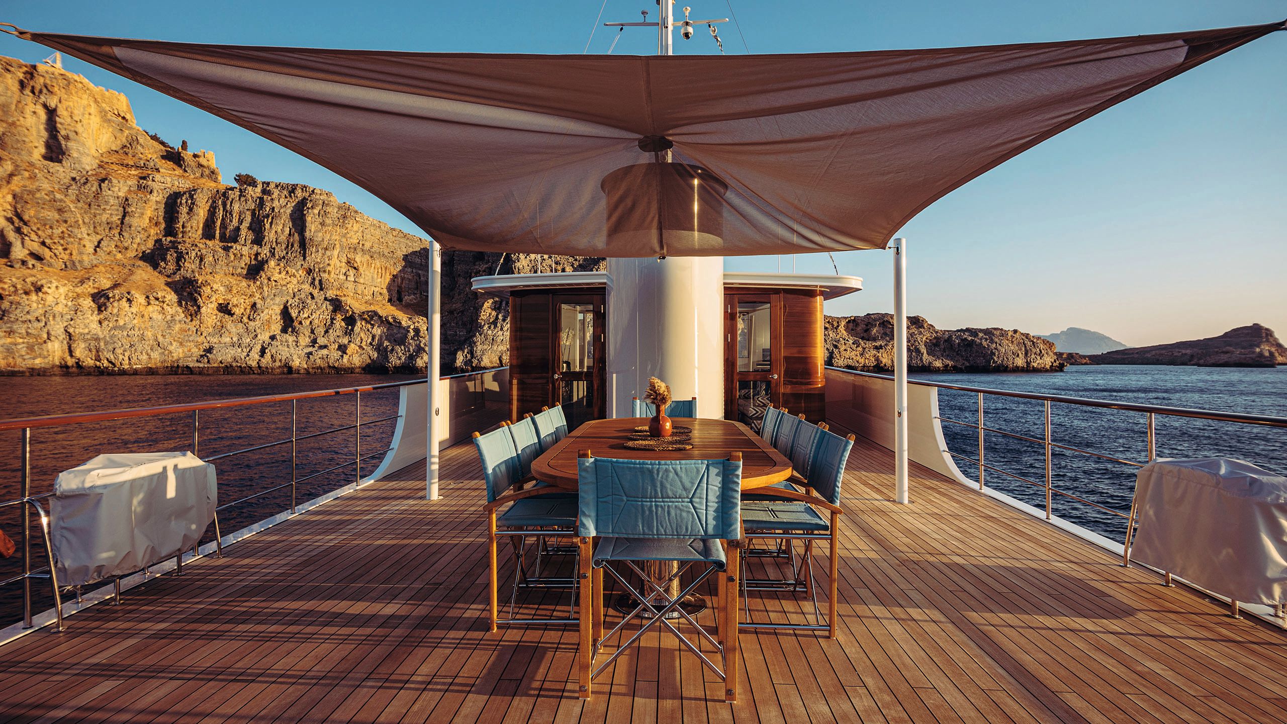 An outdoor dining area with teak table and chairs with turquoise seating