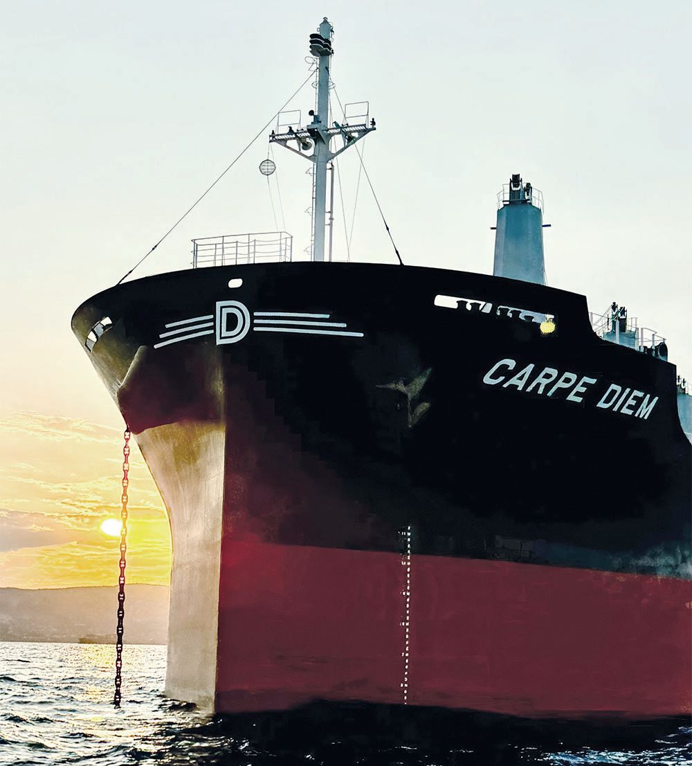 The front portion of a vessel called Carpe Diem. The bottom half is painted a dark red colour and the top is black. There's a large white capital D at the front.