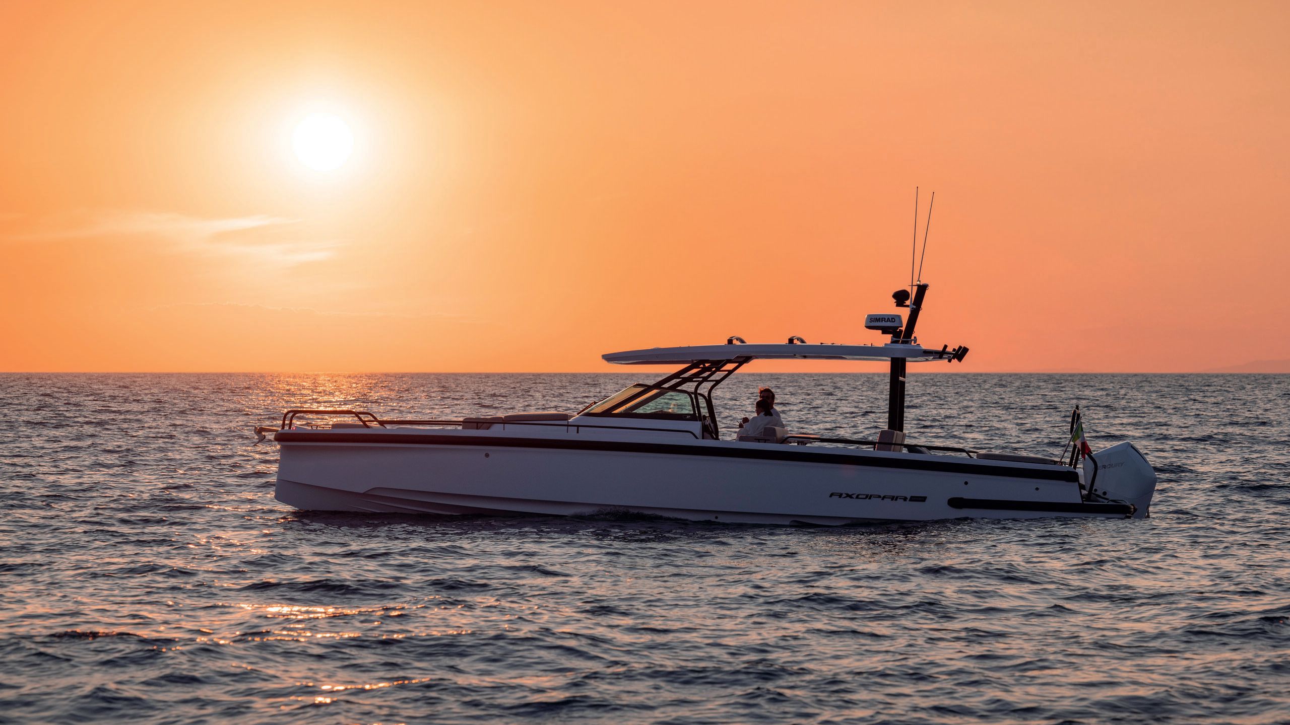 A side view of Mamma Mia on the water at sunset; the sky is a vibrant orange
