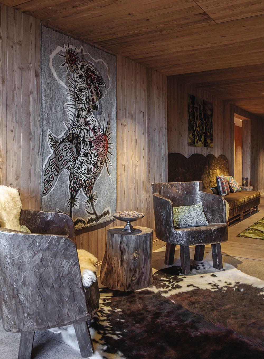Two rustic chairs on a brown and white animal hide rug. A side table made from a tree stump is between them