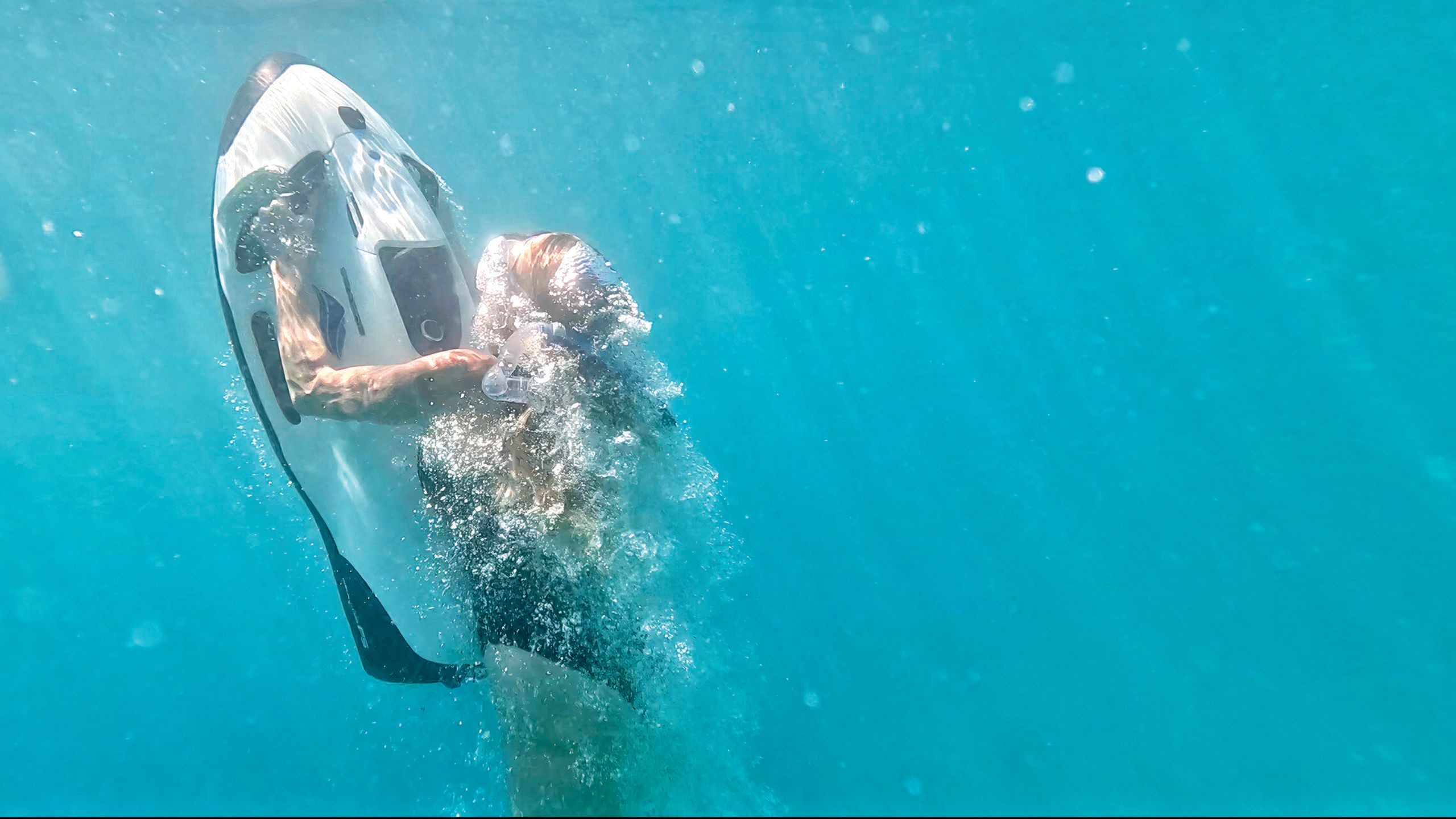 A woman underwater with a scuba mask on, heading back to the surface