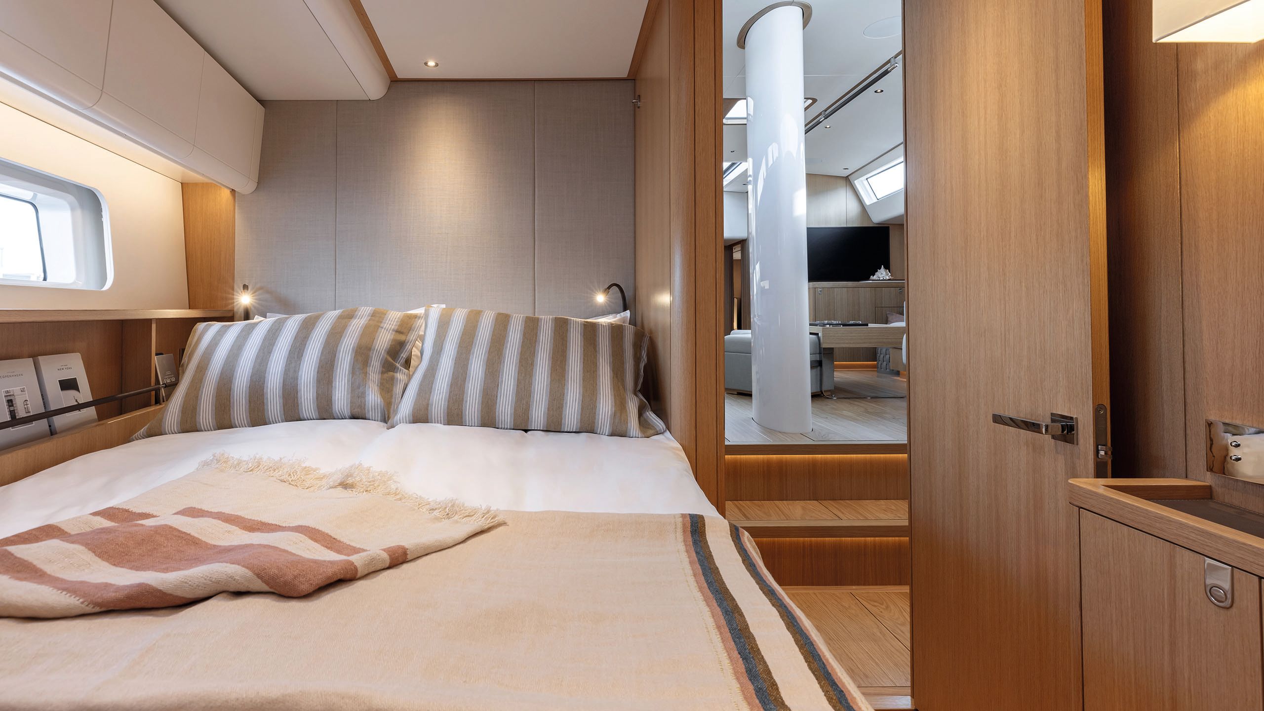 A smaller cabin with bed. There are striped throws and pillows in browns and pinks