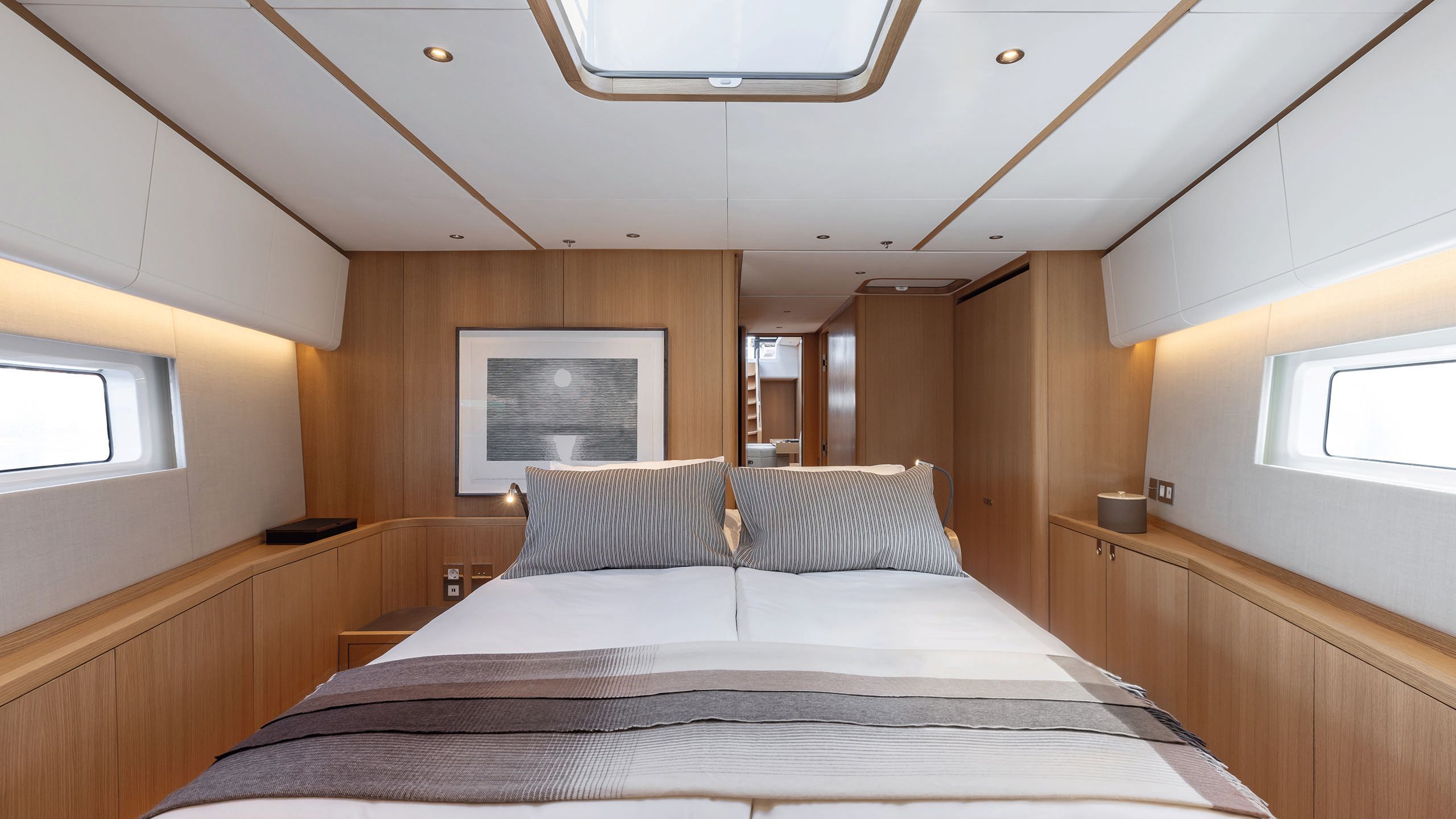 Cabin with bed in the centre. The bedding is white with grey and brown blankets and pillows