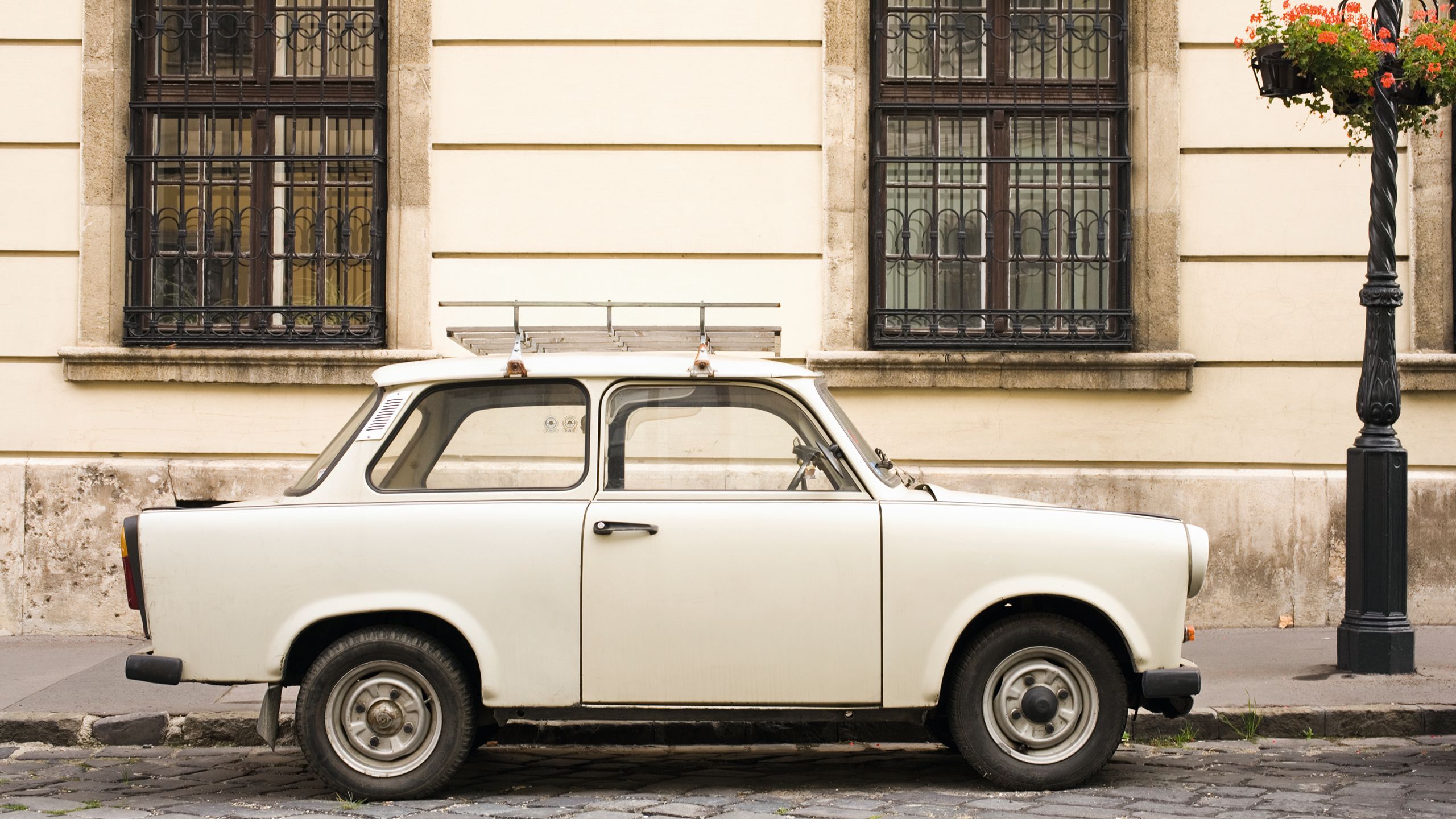 A beige Trabant parked on a street next to a beige building