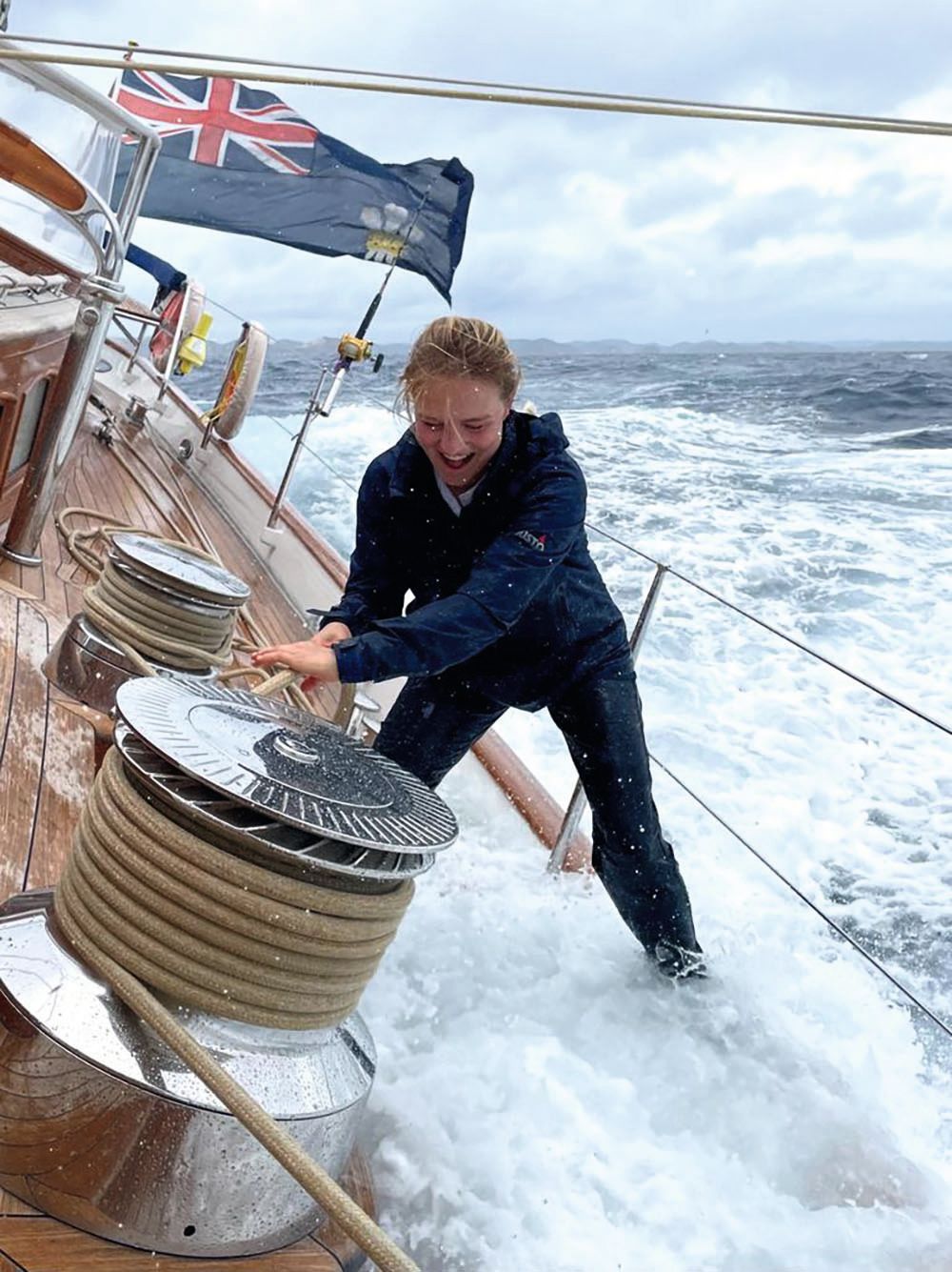 Romana on board the boat, standing by a winch. The vessel is tilting in choppy waters that have spilled on to the deck.