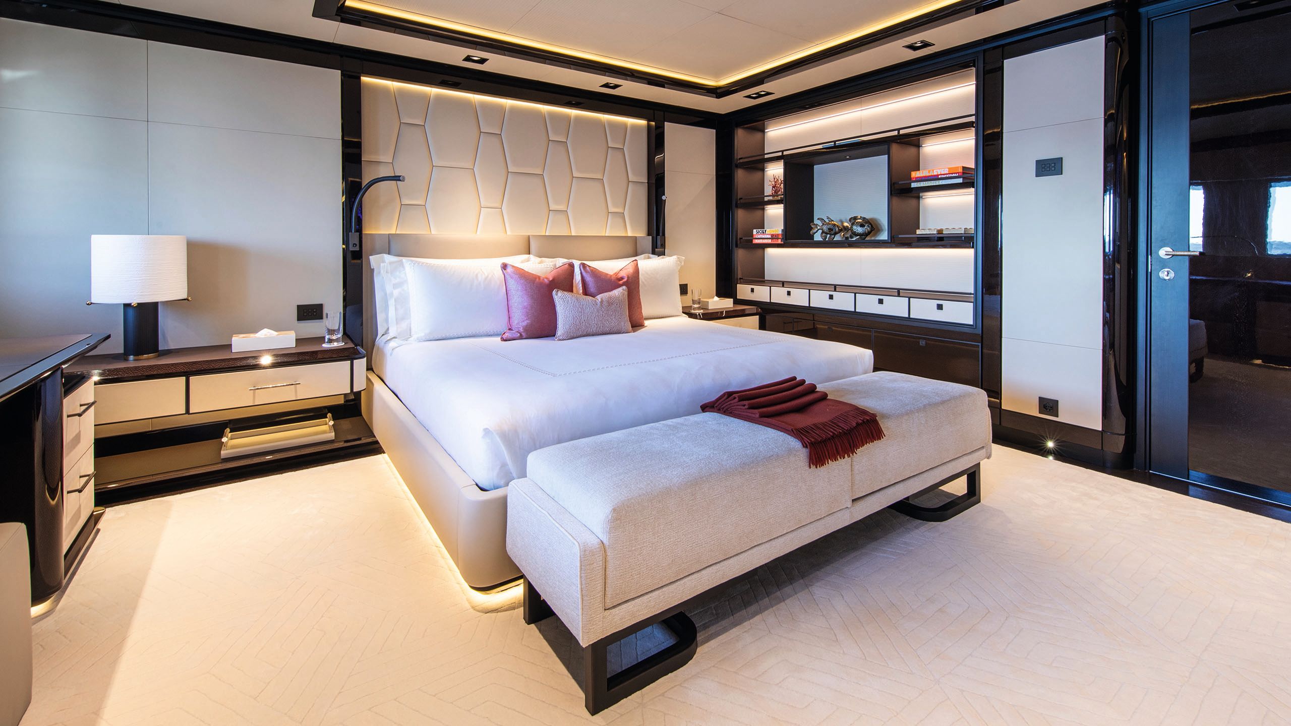 Large bed in the centre of a cabin with padded bench at the end