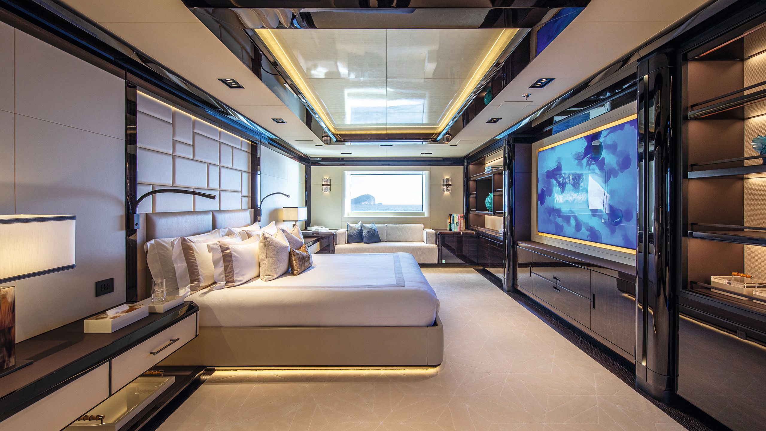 Large bed made up with neutral linens facing a large TV on the opposite wall