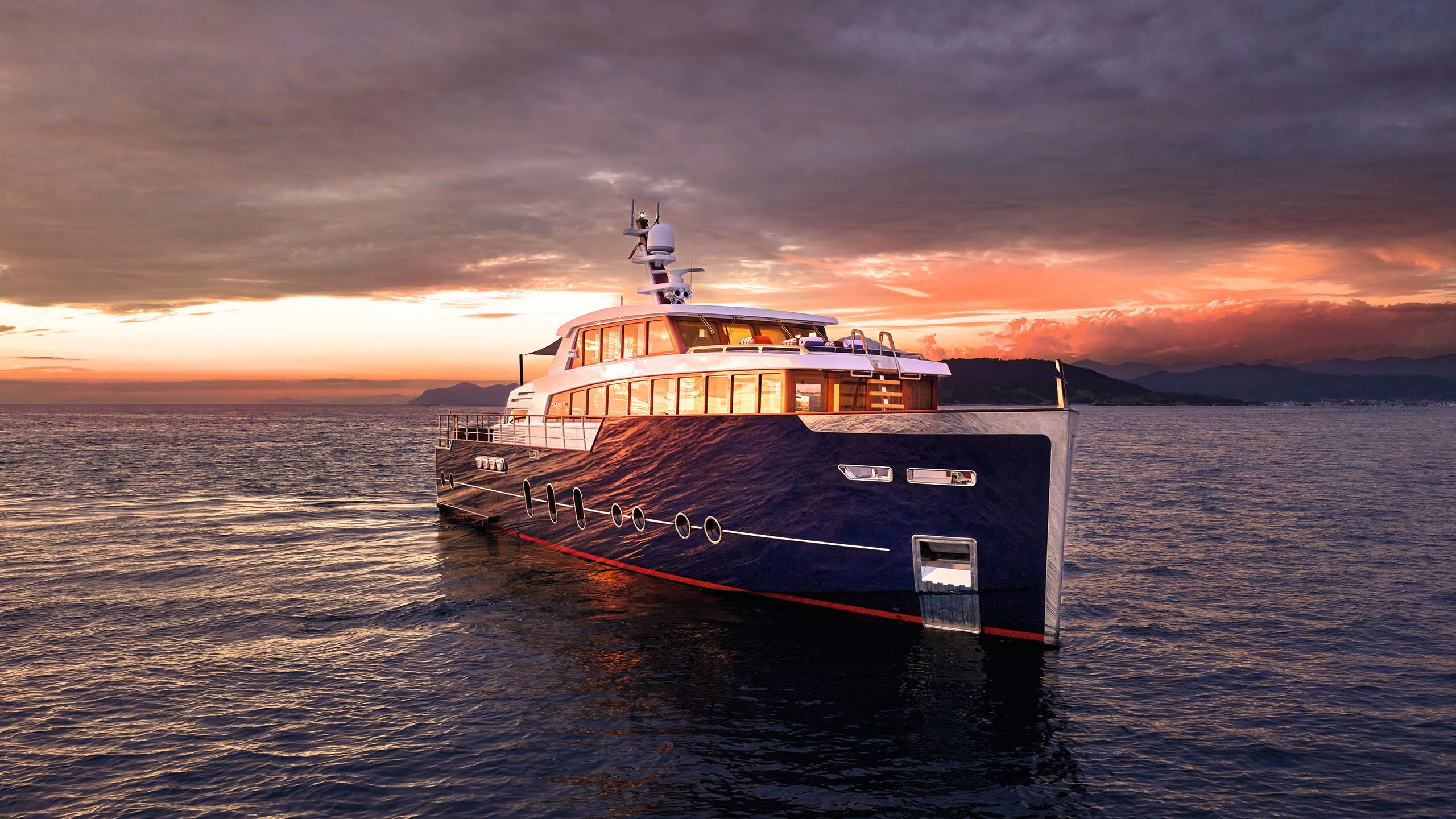 Side view of Gentleman's Yacht on the water at sunrise/sunset. The sky is dark purple with pink areas and the light is reflecting off the windows and shiny blue hull