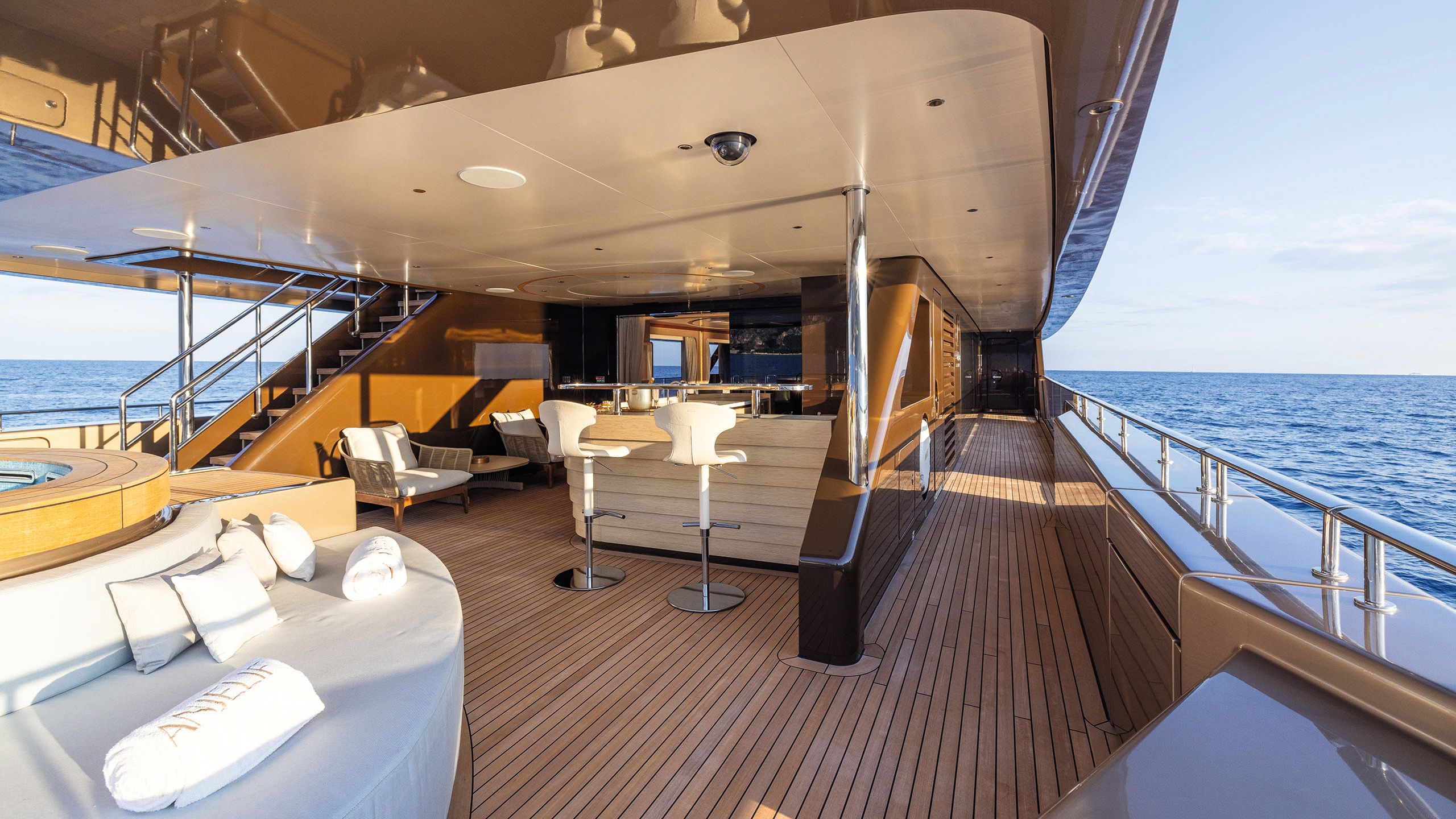 Looking towards a bar area on a deck. To the right is a circular pool with sofas around it