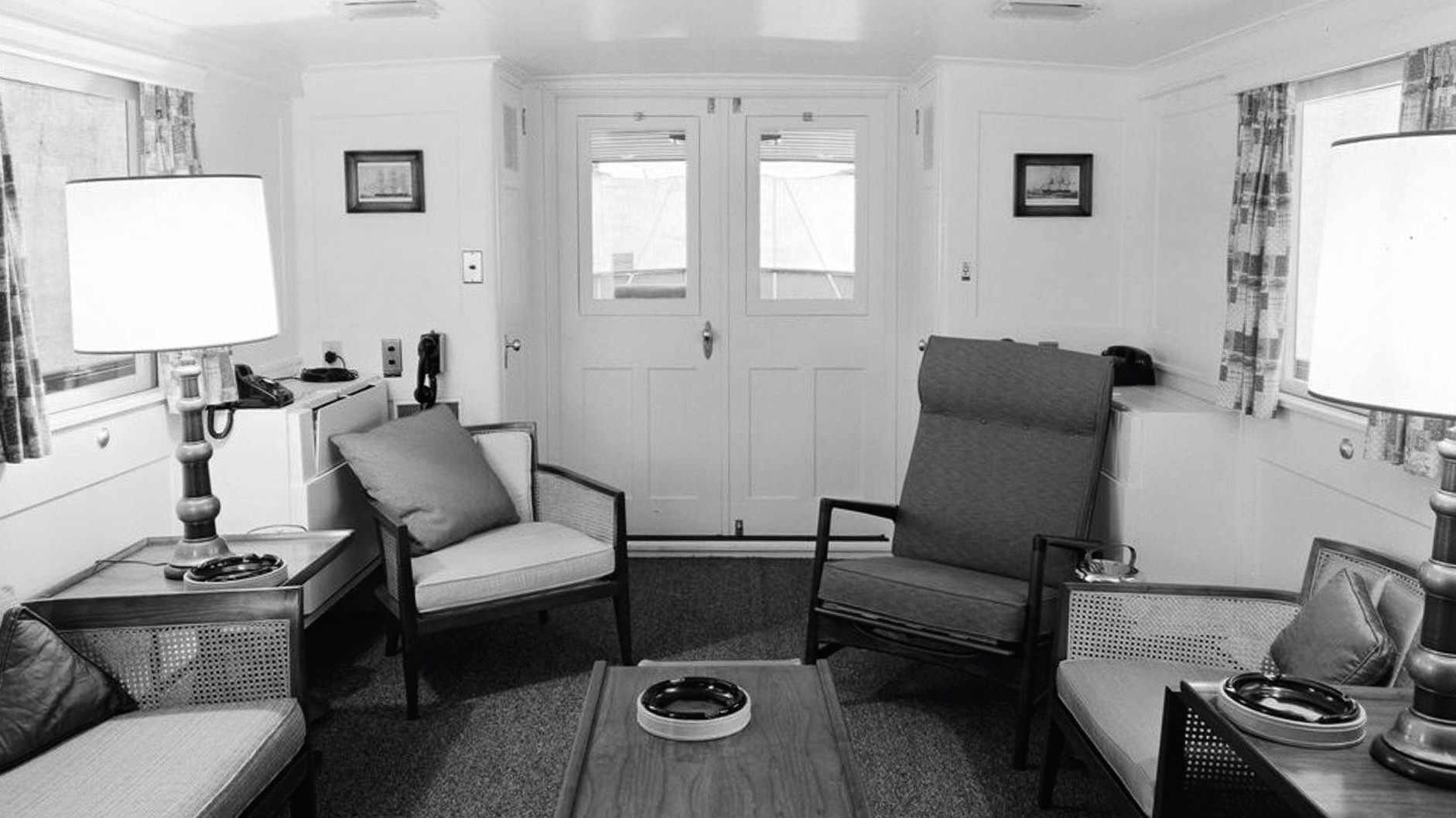 A black and white photo of the living area taken in 1961, showing mid-century chairs and furnishings