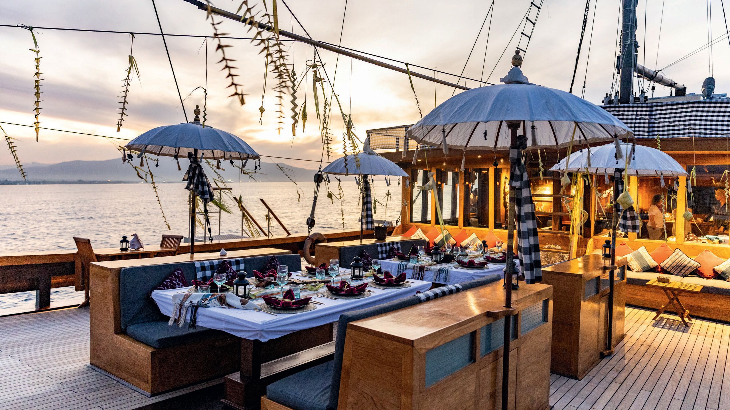 Tables with banquette seating laid out with tablecloths and traditional foods. There are small parasols dotted around