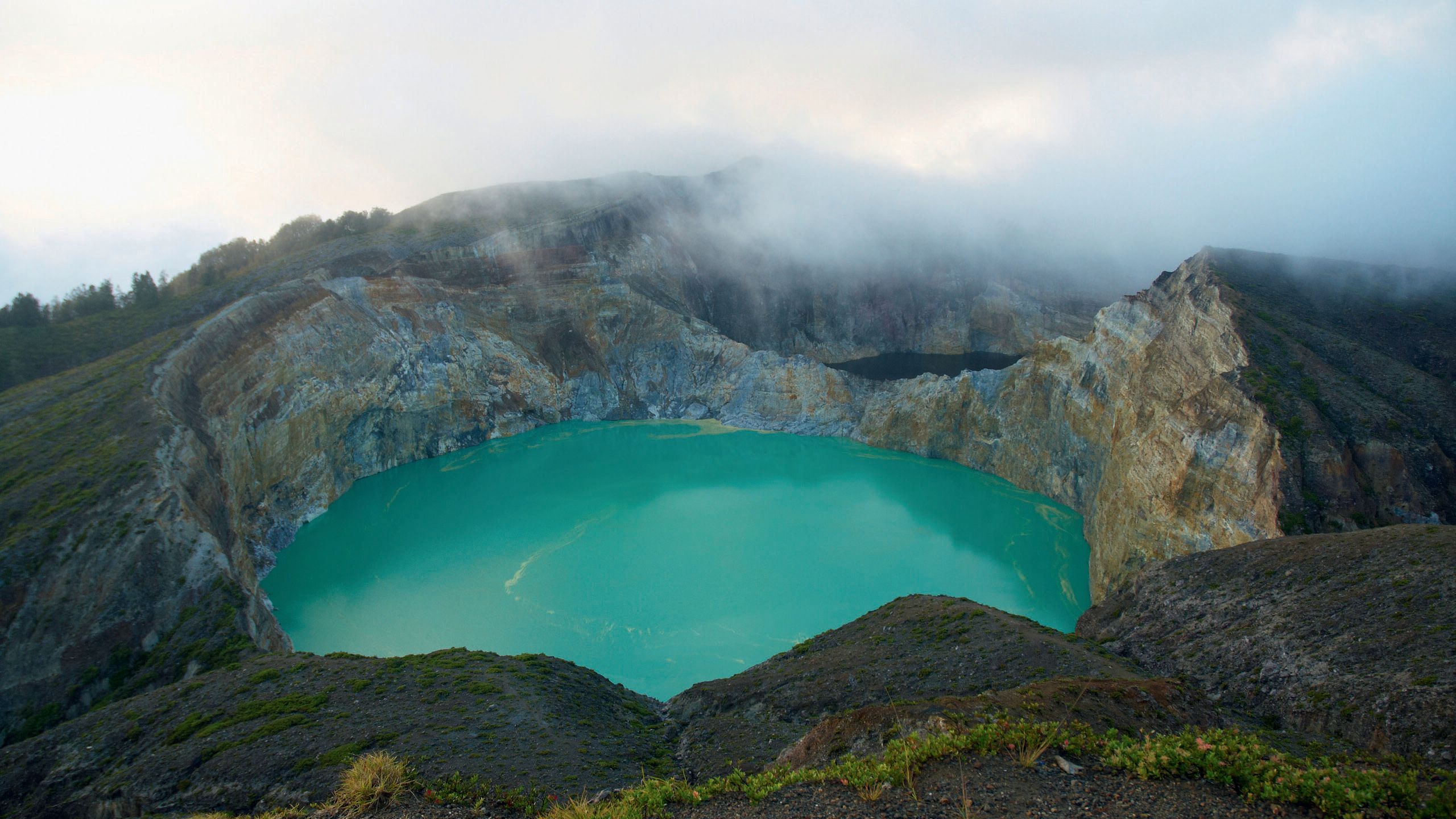 Overhead view of a large, turquoise natural pool of water surrounded by rocks