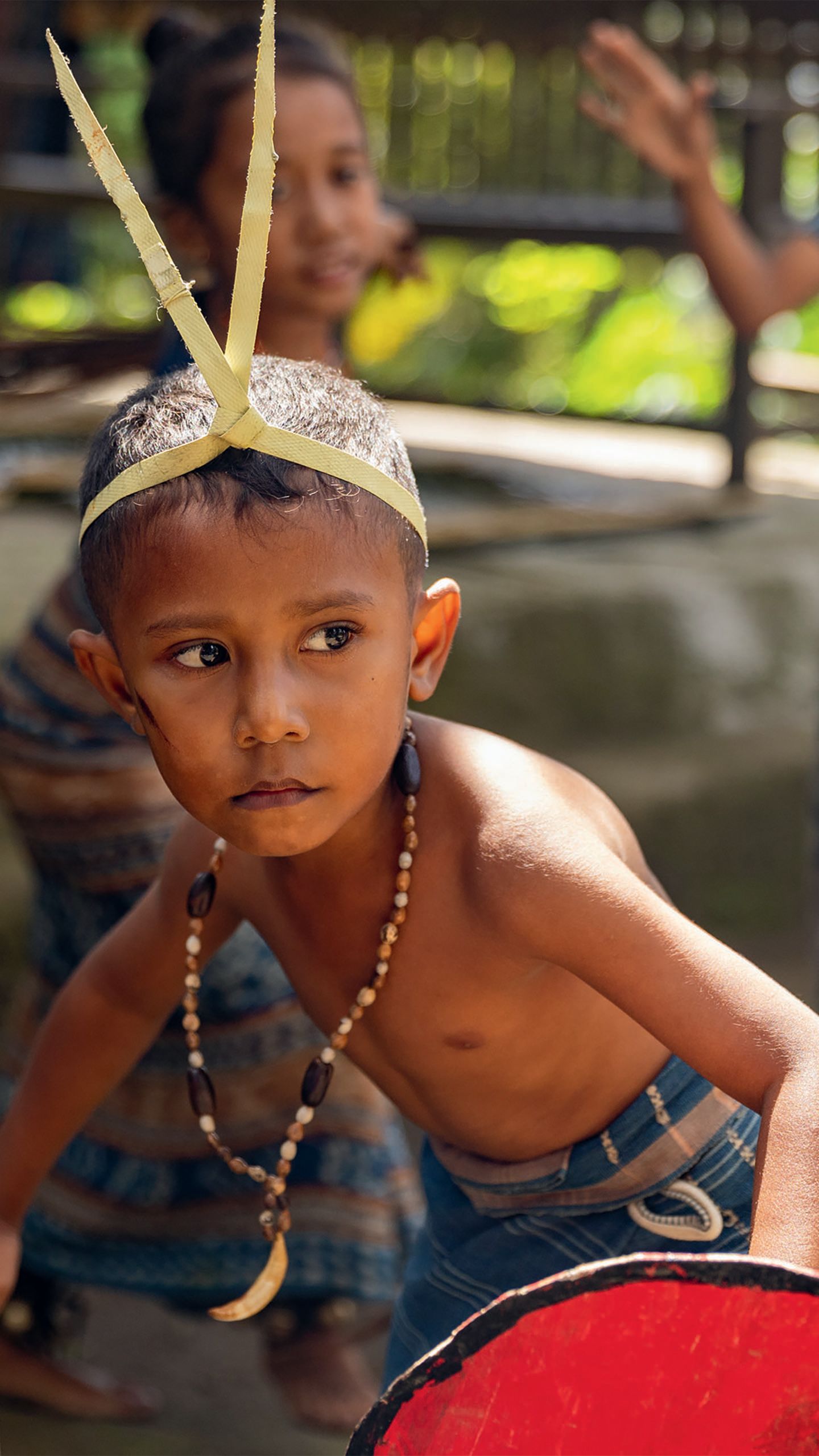 A young boy in traditional dress, jewellery and headwear