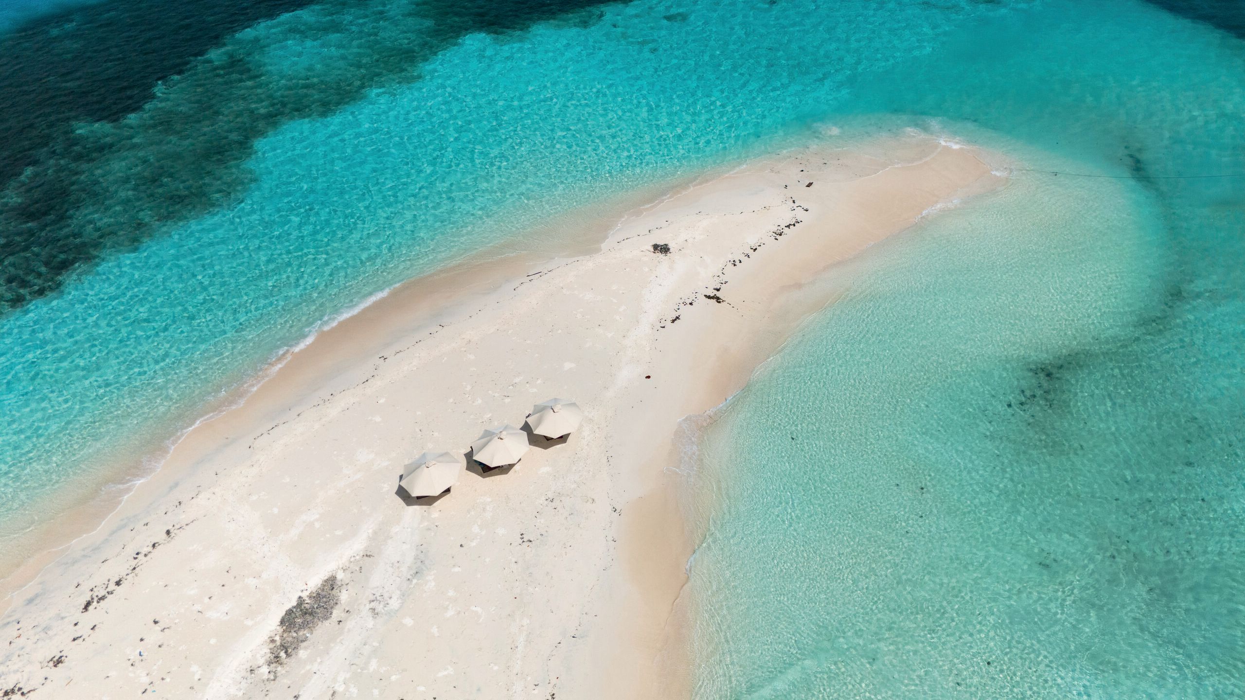 Overhead view of a spit of sand stretching out into turquoise shallows