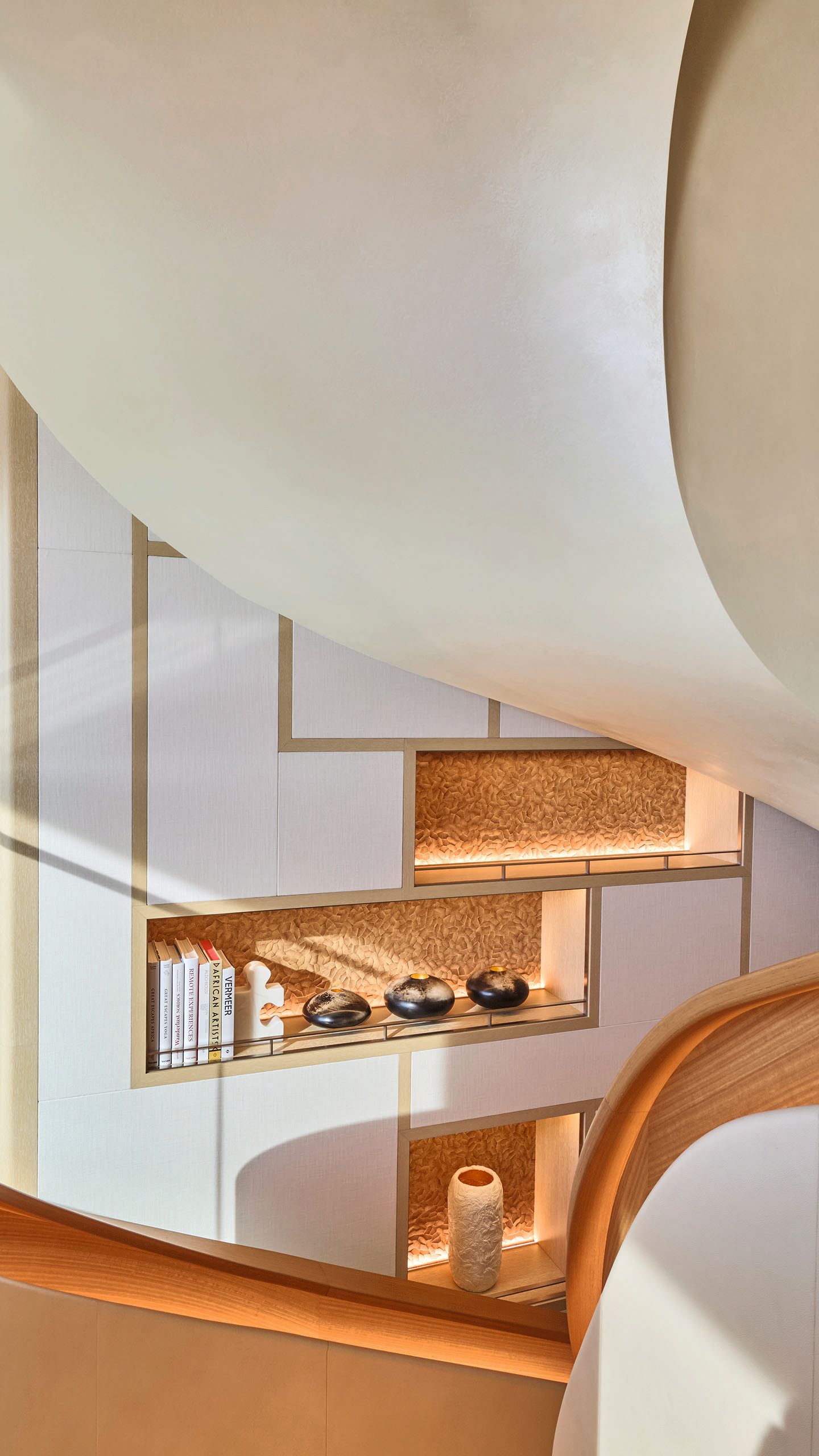 Looking towards the side of a curved staircase which has pockets cut into the wall for shelving