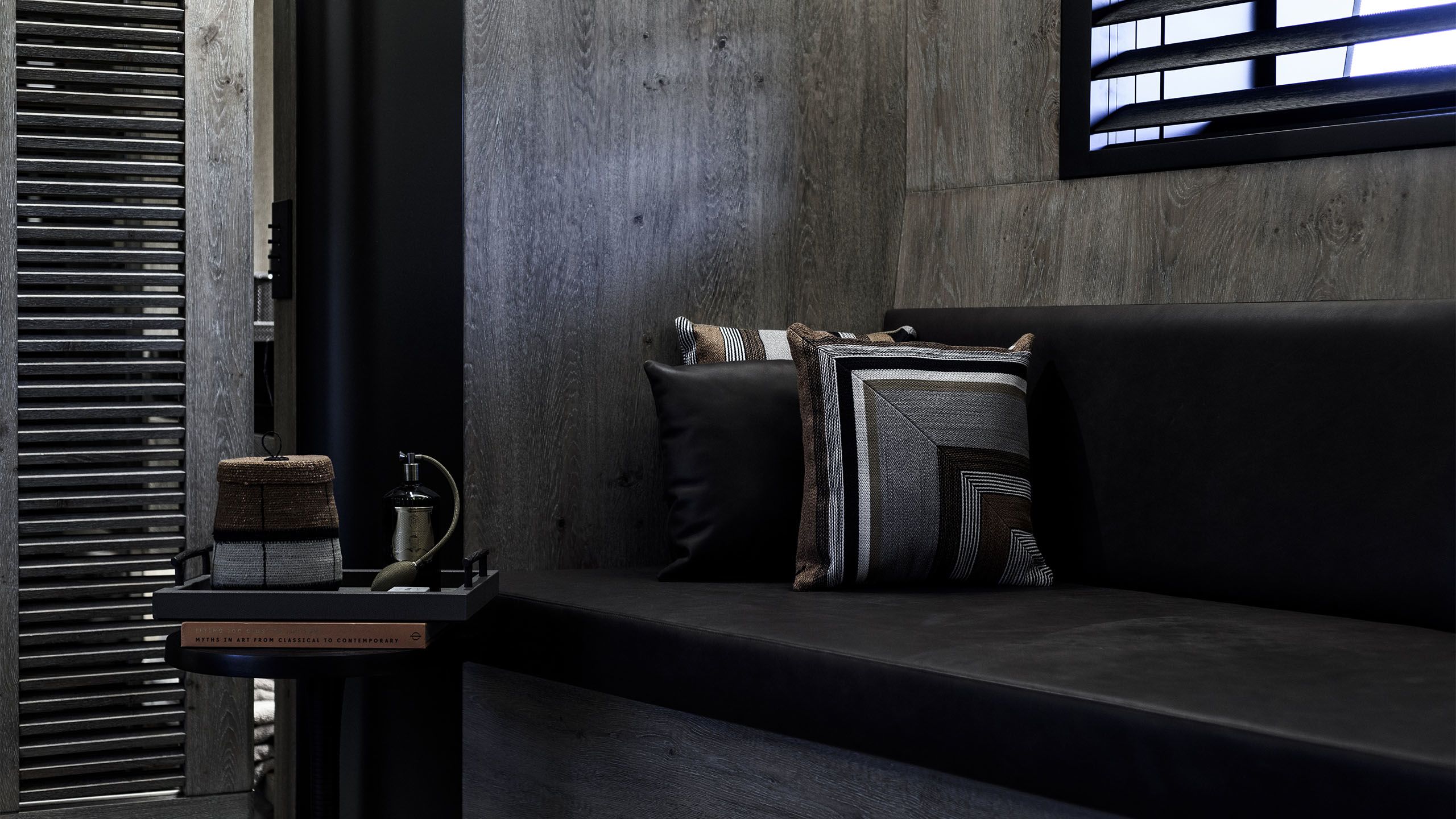 Black banquette-style seat with cushion featuring geometric print