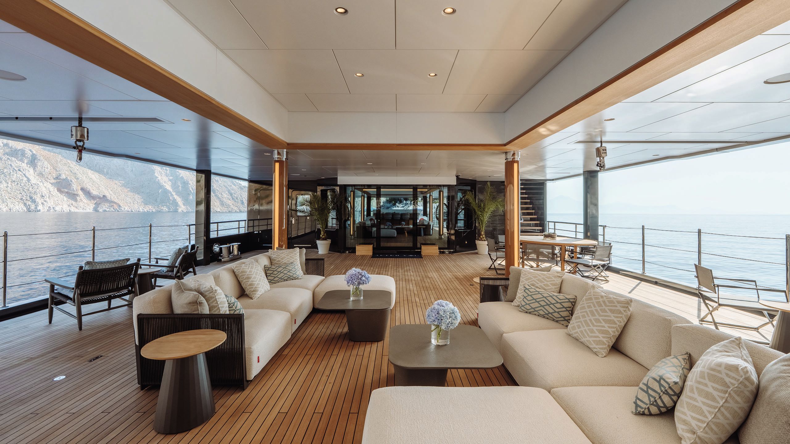 A covered outdoor deck with two beige corner sofas facing each other