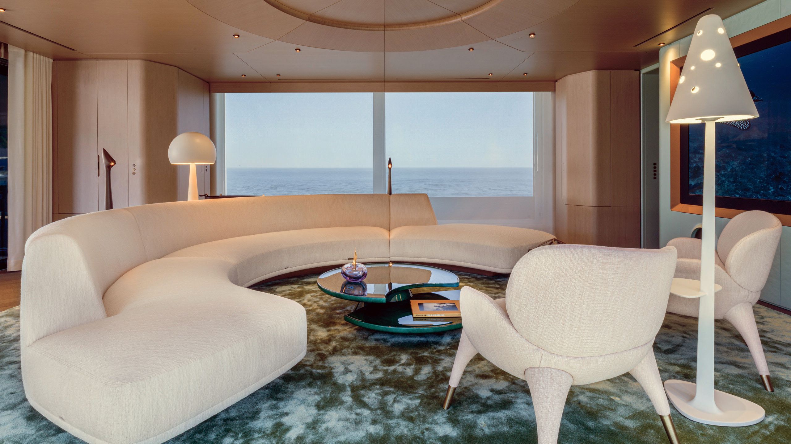 Large curved sofa in beige with matching armchairs and tall mushroom-shaped lamps in off-white