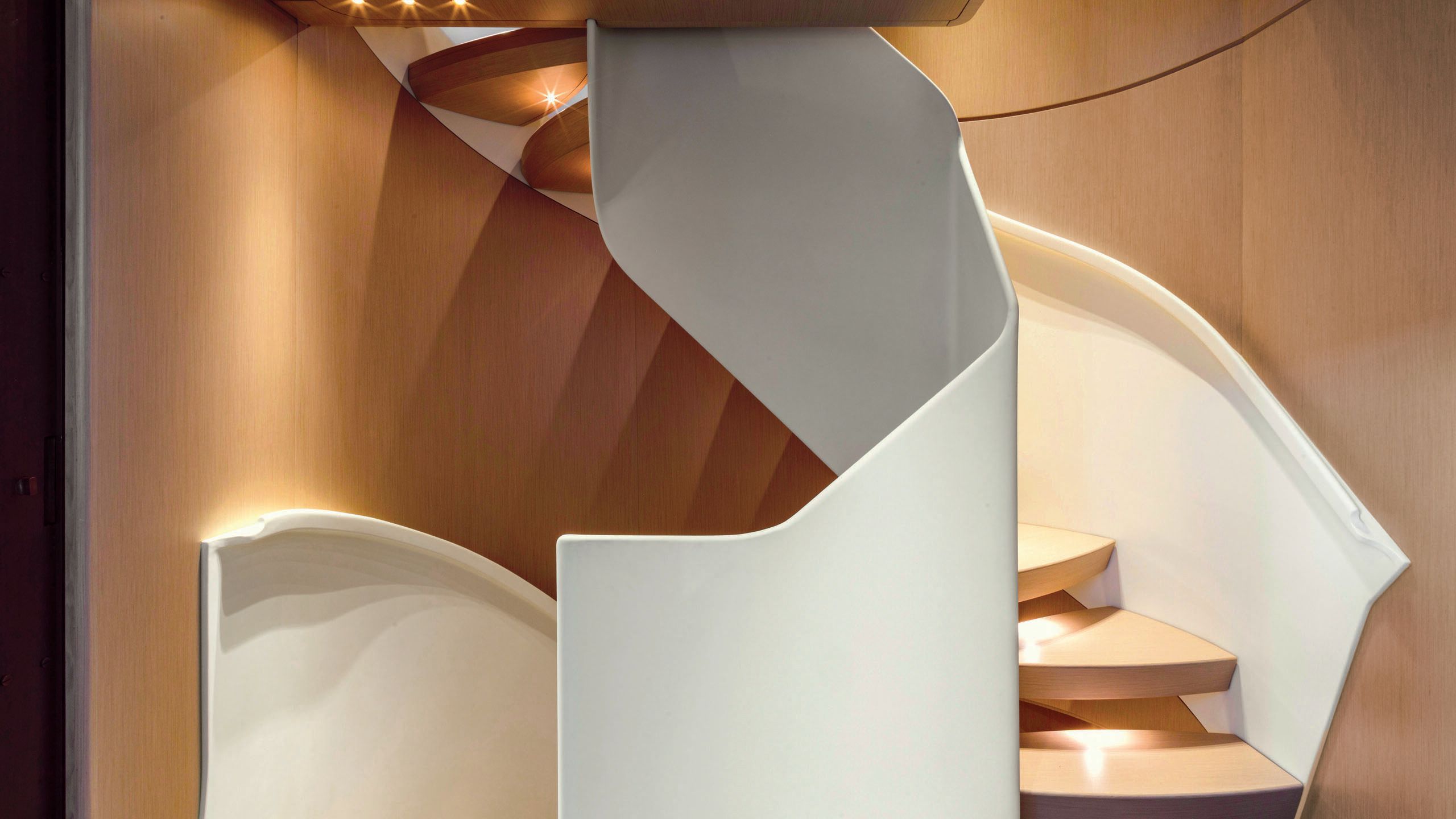 A curved staircase with white abstract moulding around the side