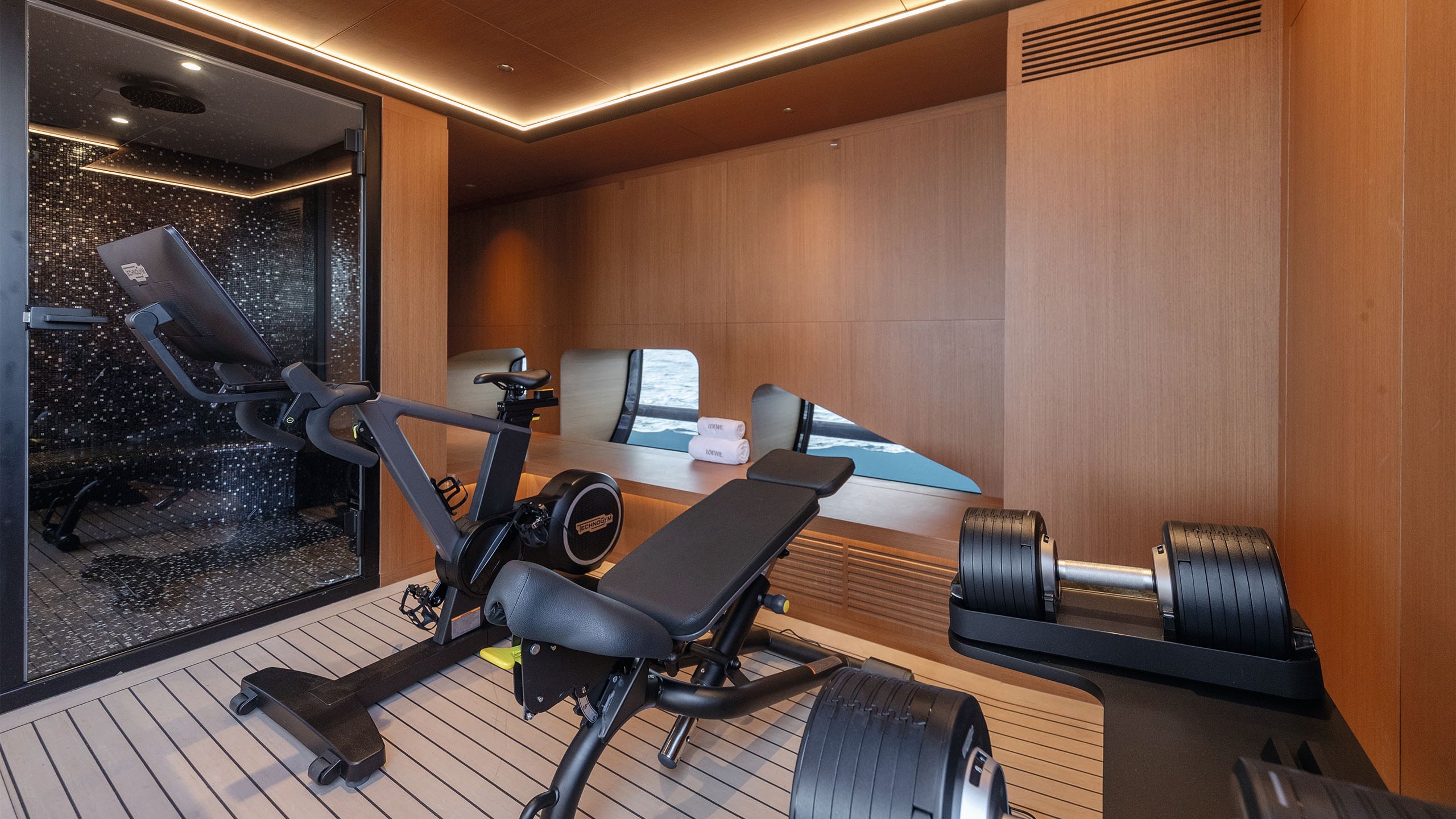 Inside the gym which has an exercise bike, bench and dumbells