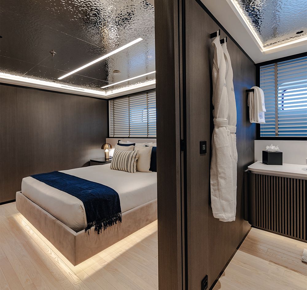 Looking from a hallway into a guest room which is made up with neutral sheets and a dark blue throw