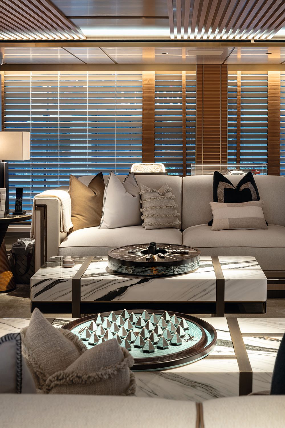 Lounge area on board a boat. It has neutral decor and a mint green game laid out in front of a sofa