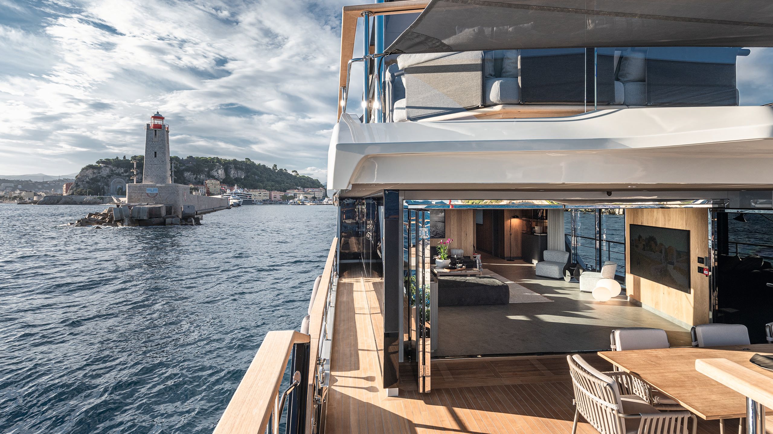 Looking down the side of a deck - a dining table and chairs is in the foreground and an indoor lounge area is in the background