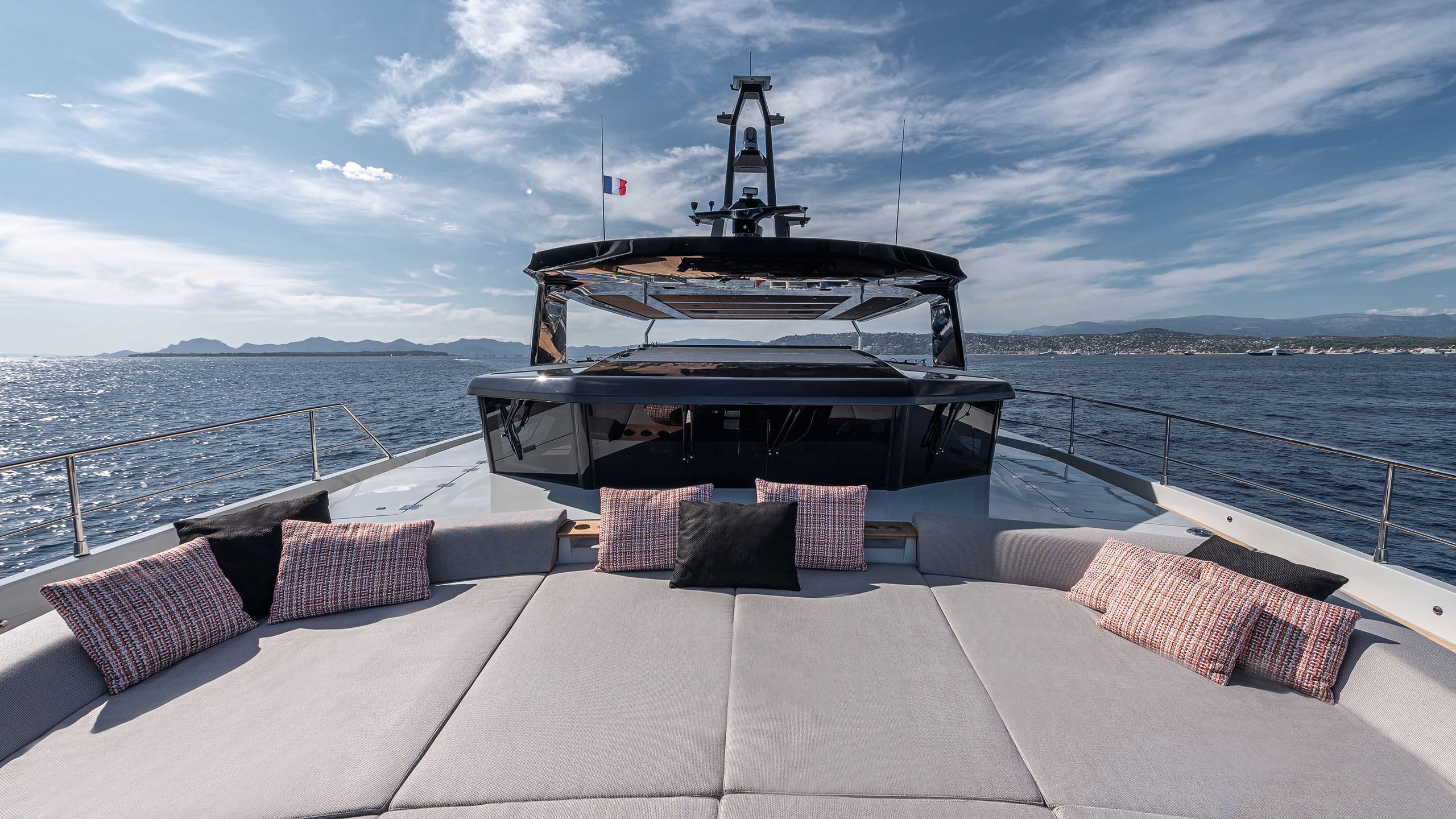 Front view of a large sunpad area with grey cushions and pink/red throw cushions