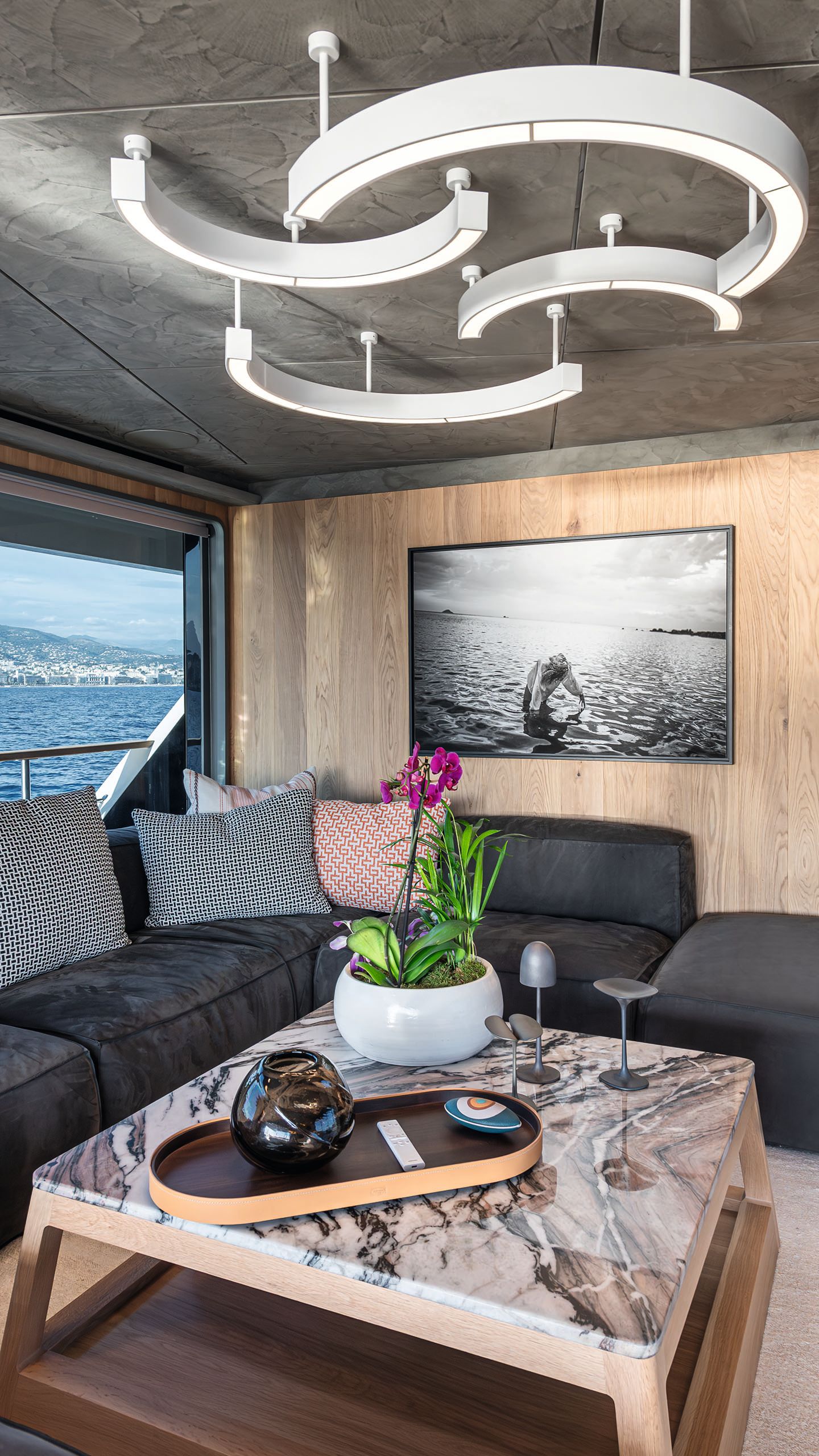 Marble effect square coffee table in front of corner sofa. An abstract white light fixture is on the ceiling overhead